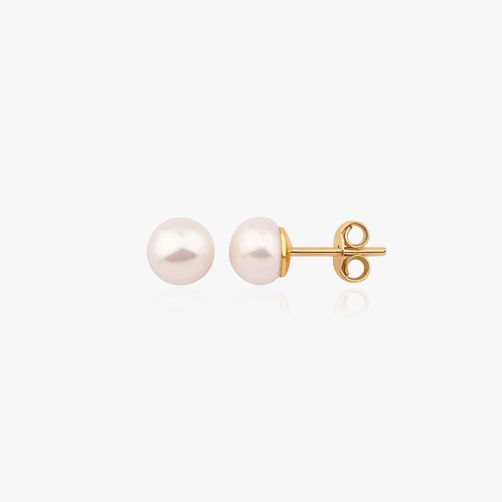 A pair of white pearl stud earrings set in 14K yellow gold, one of them shown sideways.