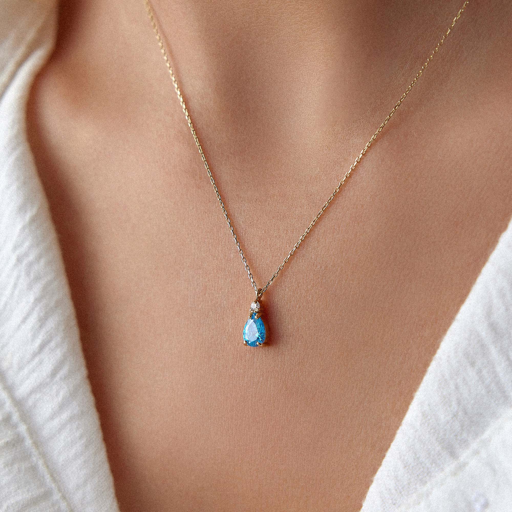 Necklace with a blue drop pendant worn by a person