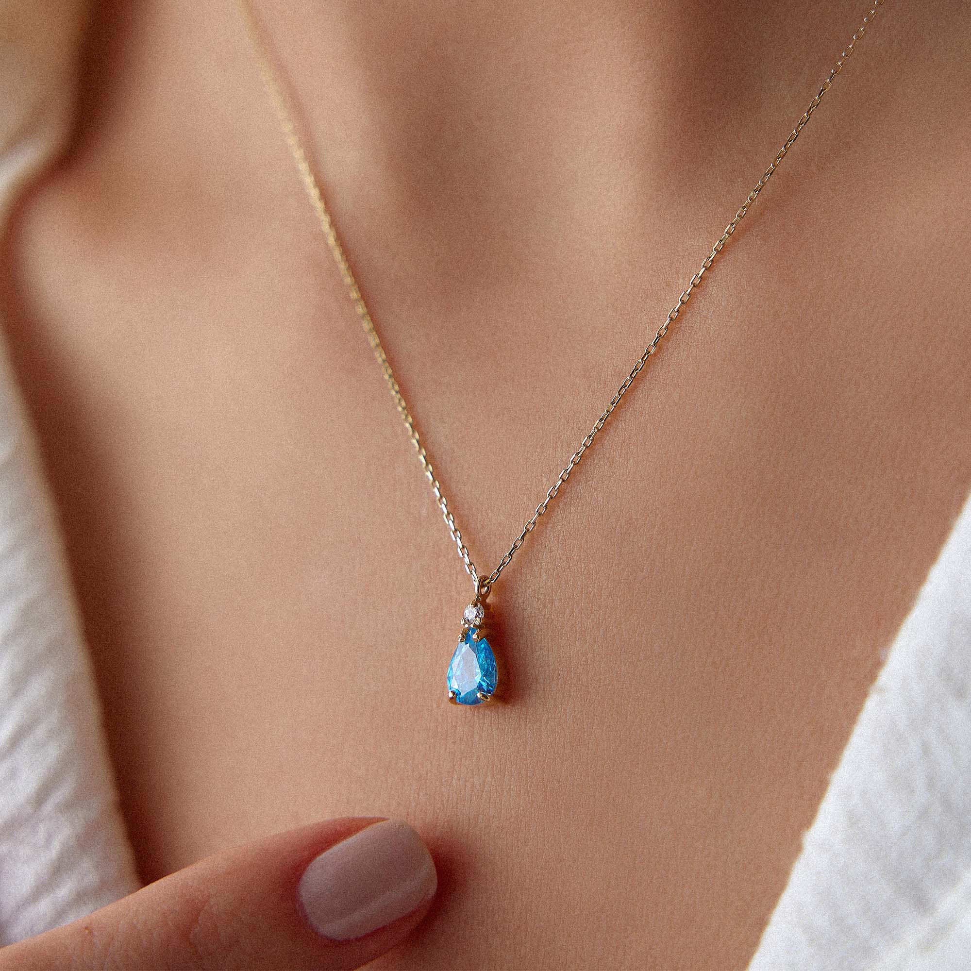 Necklace with a blue drop pendant worn by a person