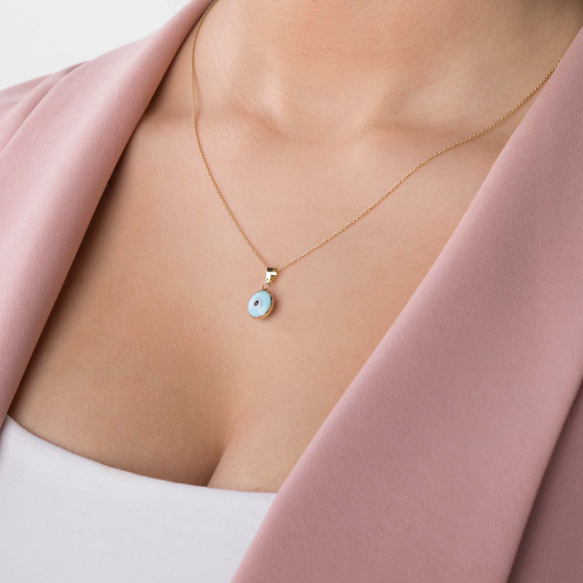 A model wearing a baby blue evil eye pendant on a chain