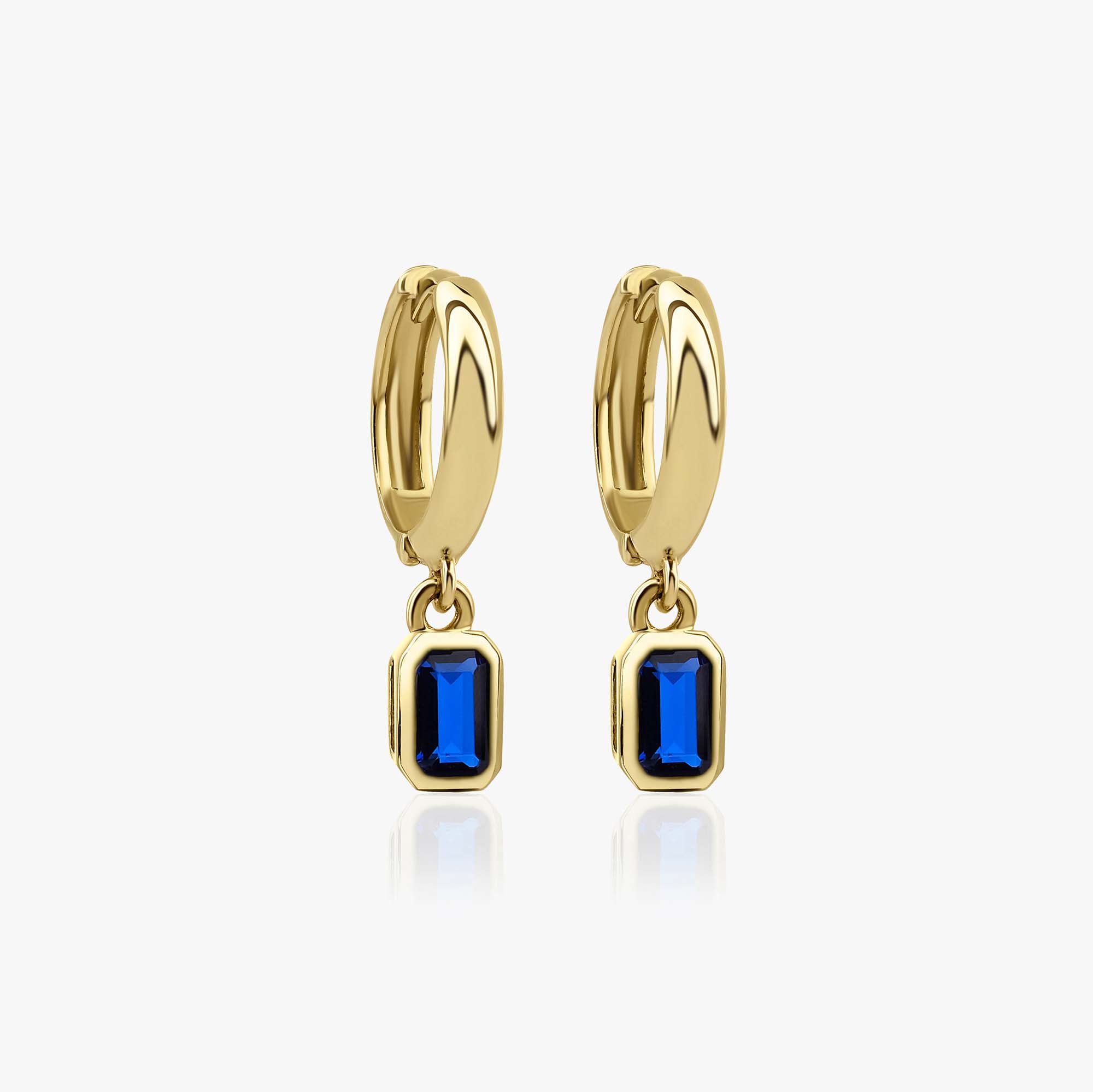 Gold hoop earrings with blue gemstones on a white background