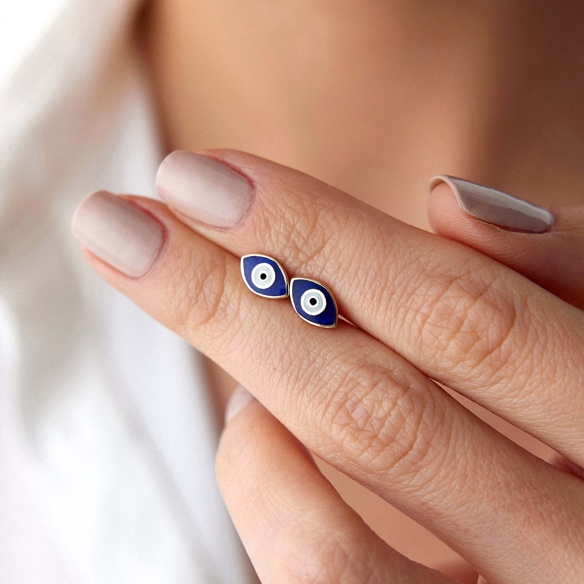 A hand holding a pair of chubby evil eye studs.