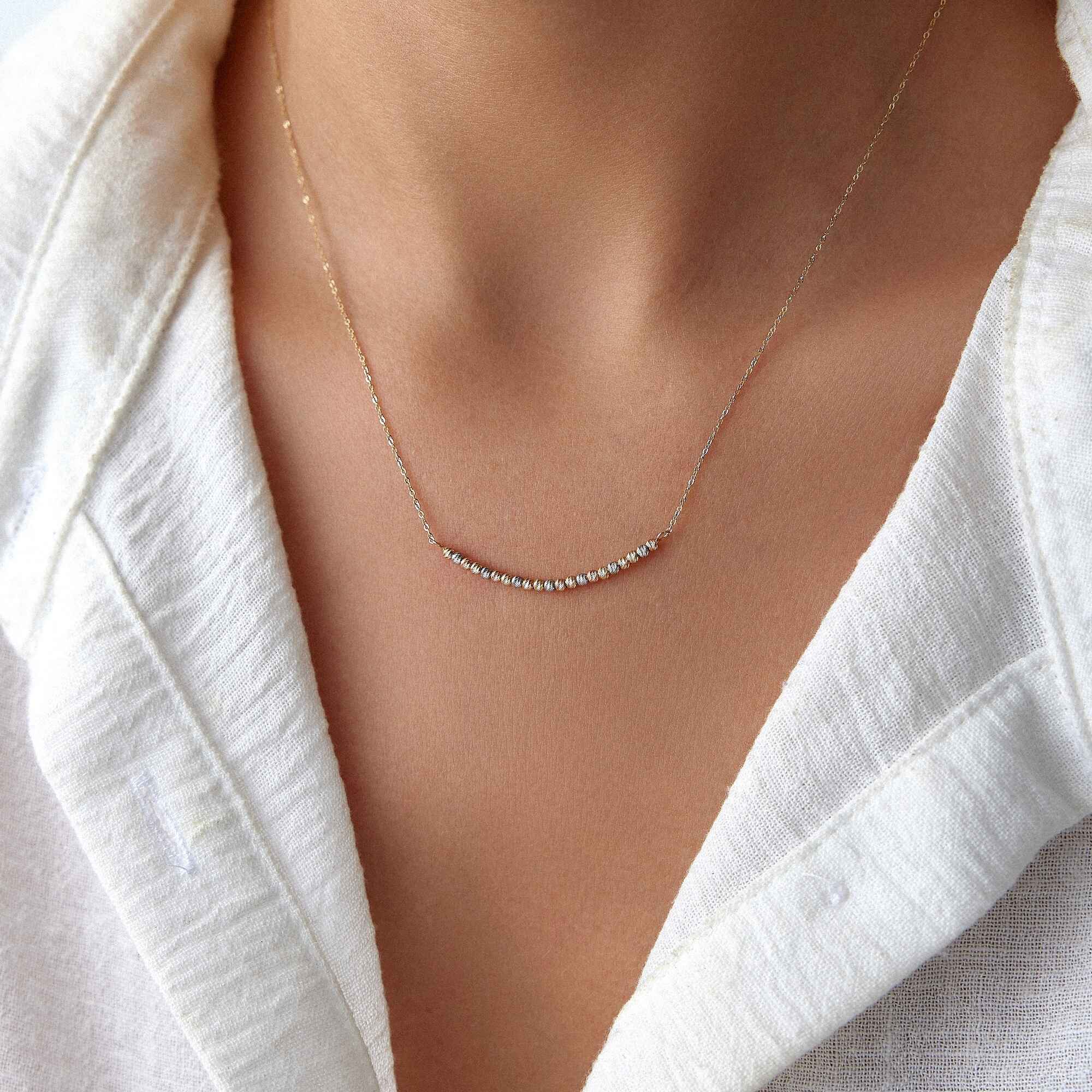 A model wearing a 14k gold curved bar necklace.