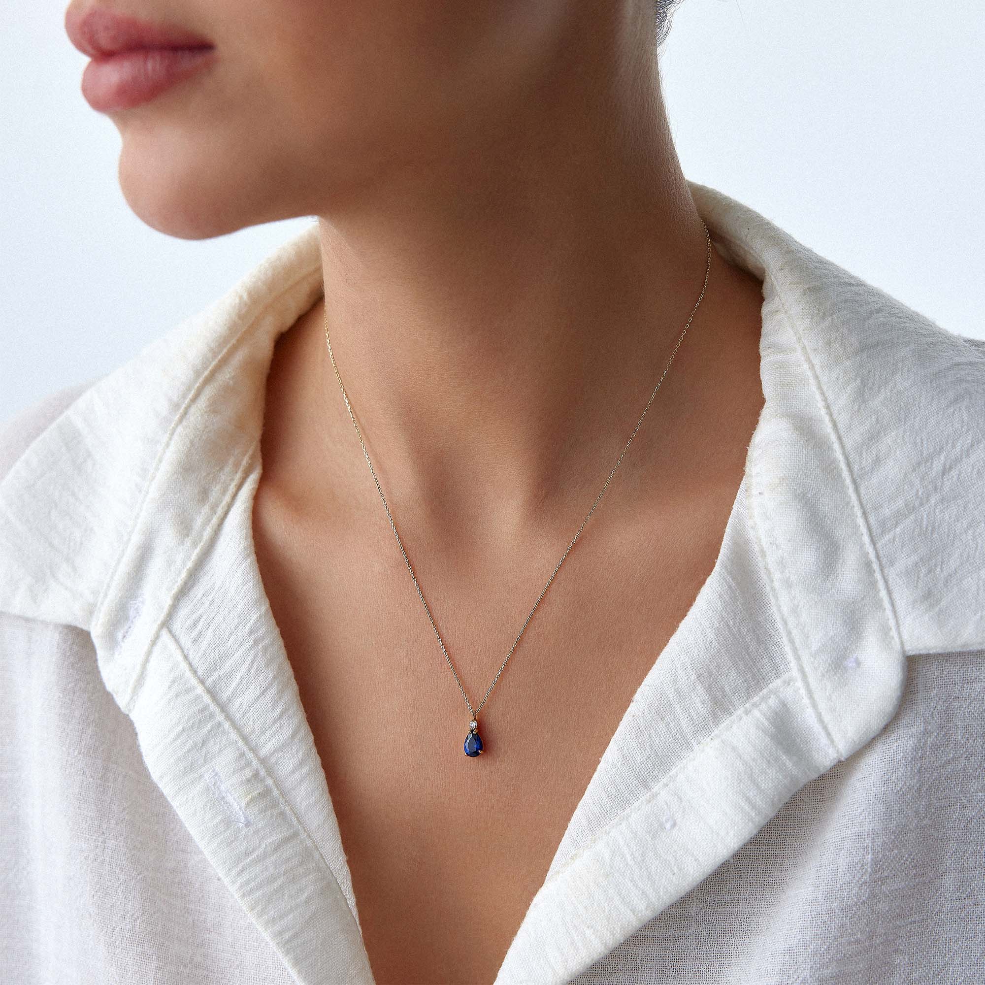 A model wearing a dark blue drop necklace.