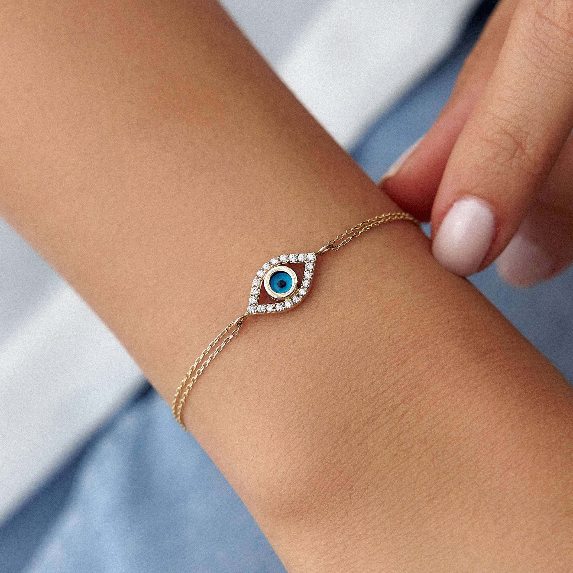 14K Gold bracelet with an eye design on a wrist against a light background