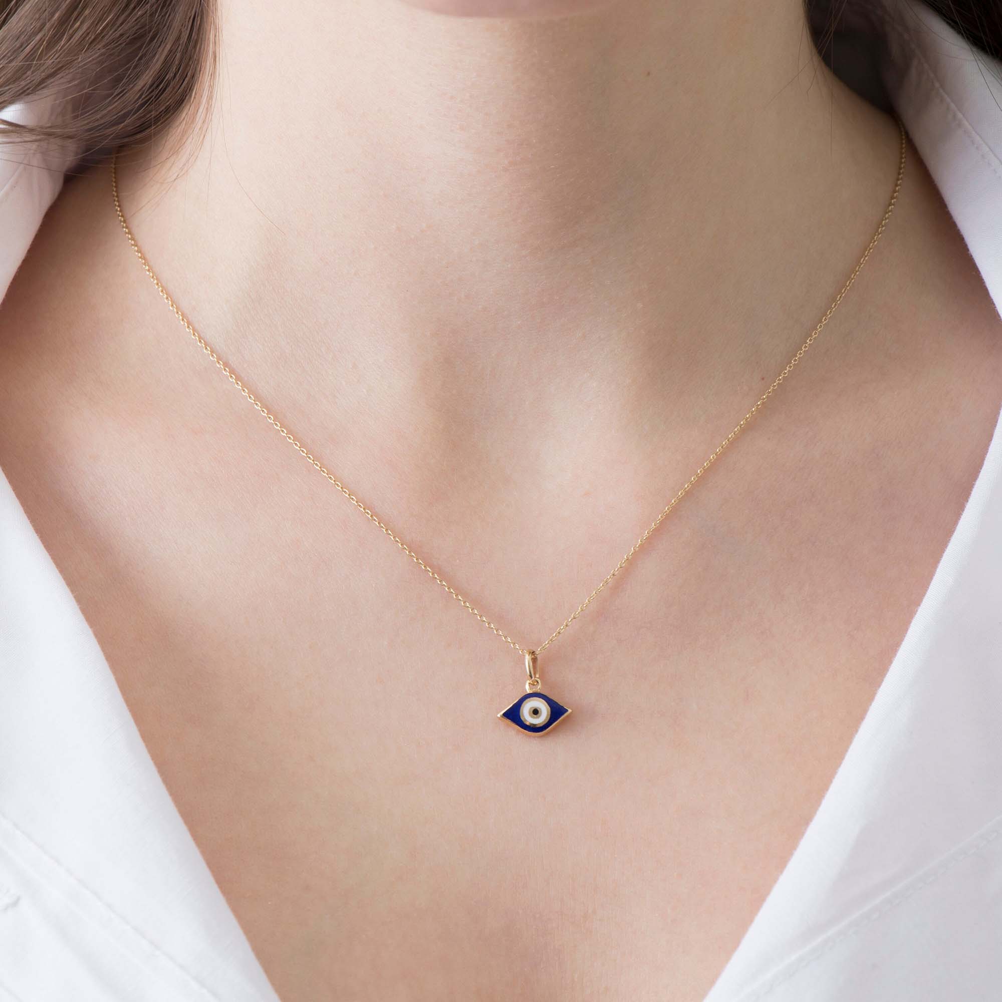 A model wearing an elongated navy blue evil eye pendant on a thin gold chain.