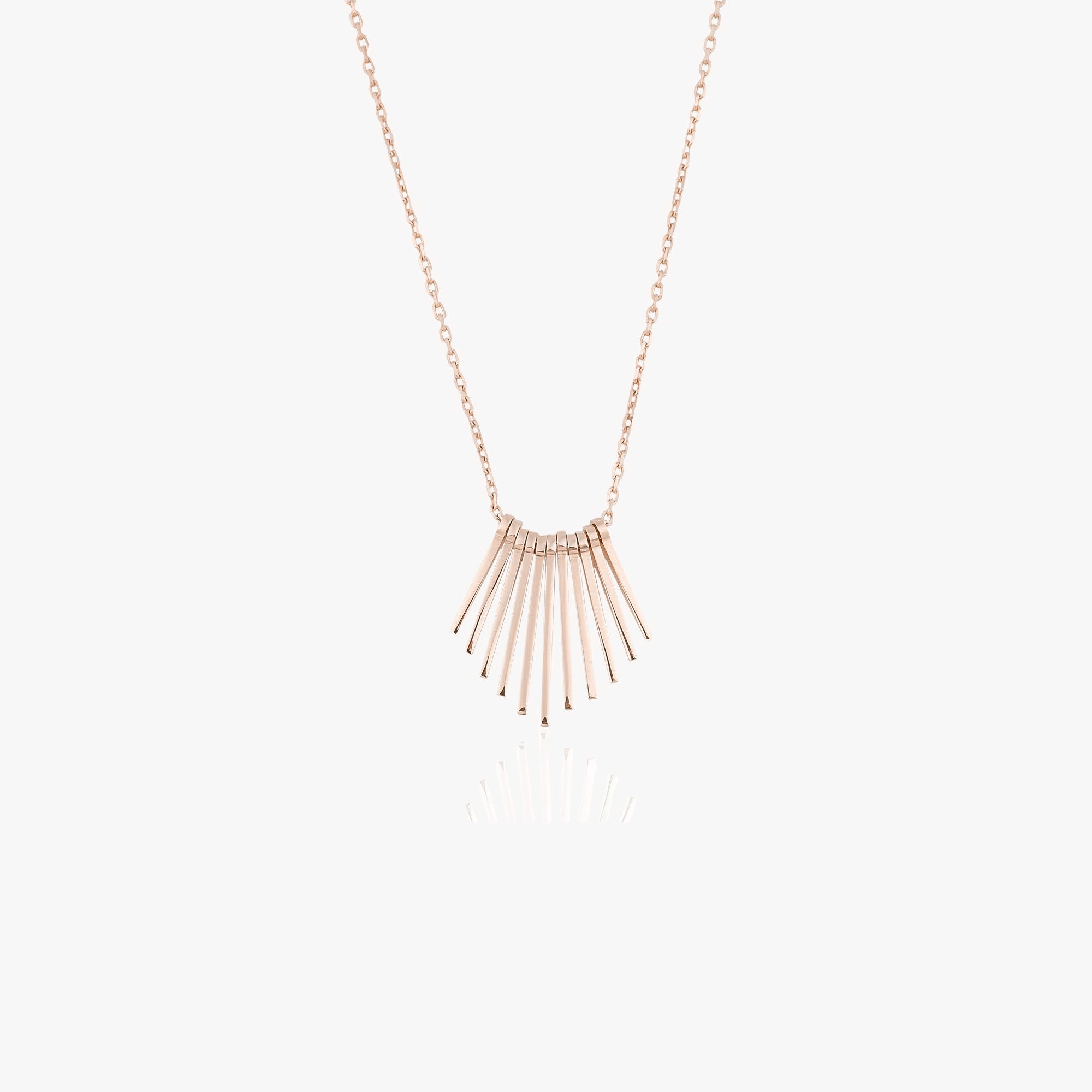 A 14k rose gold necklace with several spikes create the illusion of a sunrise shown on a white background.