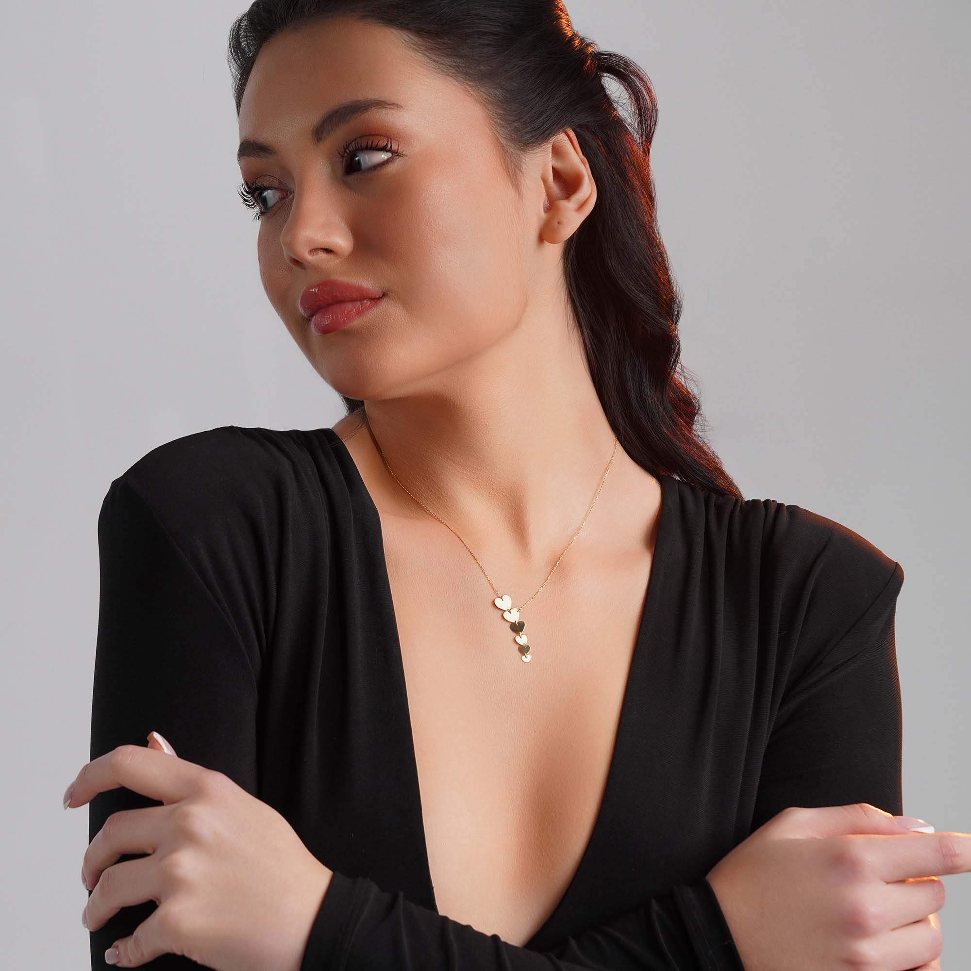 A graduated heart lariat necklace worn by a model.