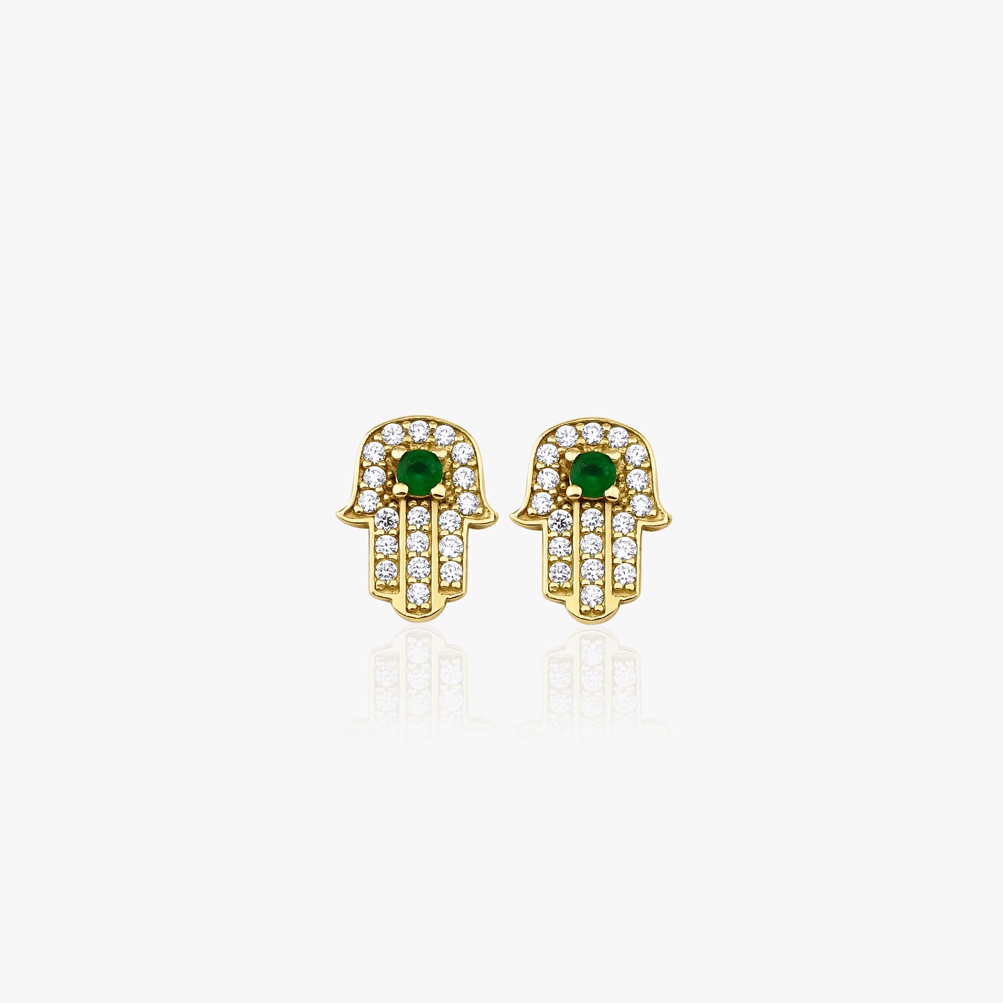 a pair of 14k yellow gold hamsa studs with green central stones on a white background