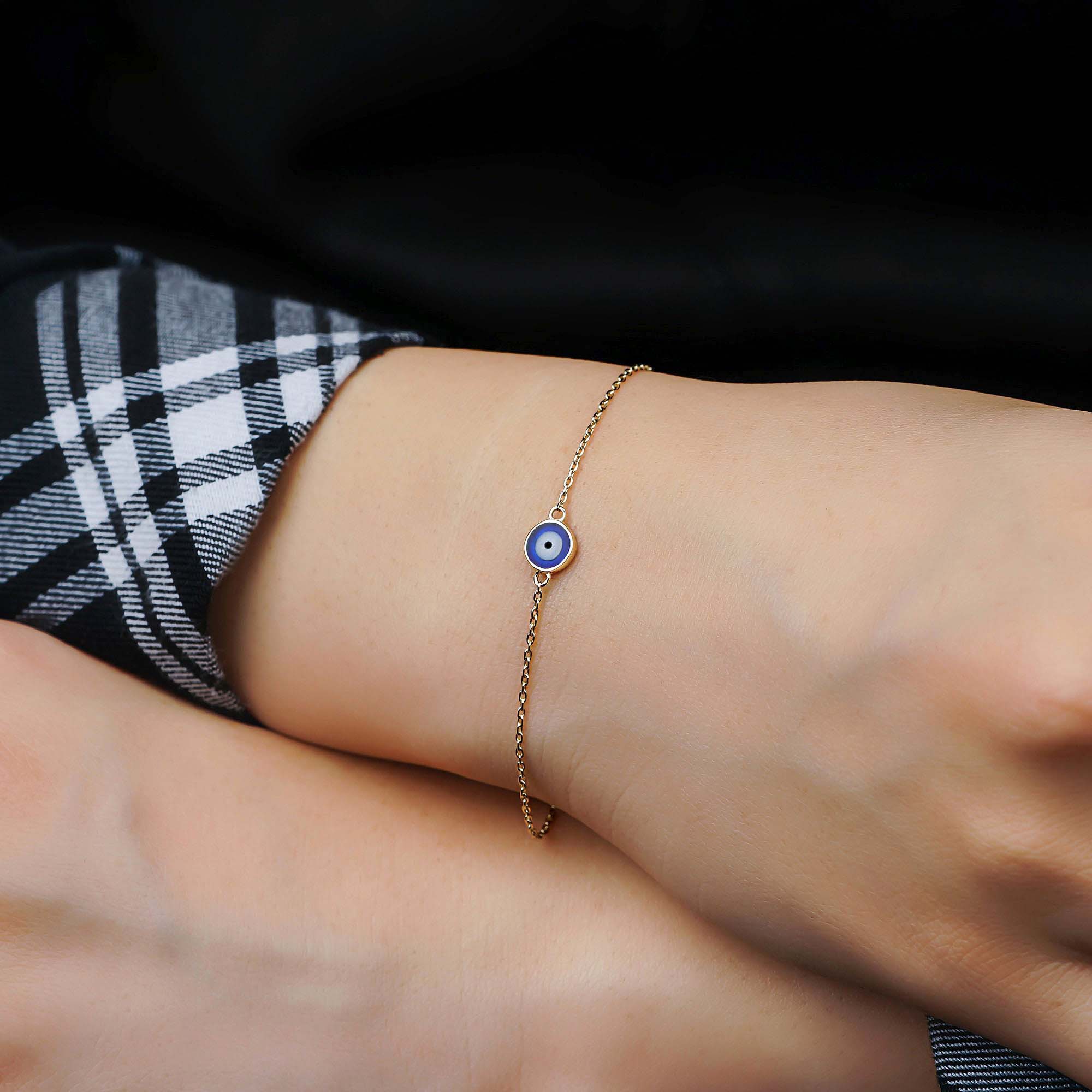 A navy blue evil eye bracelet with 14K gold, displayed on a wrist.