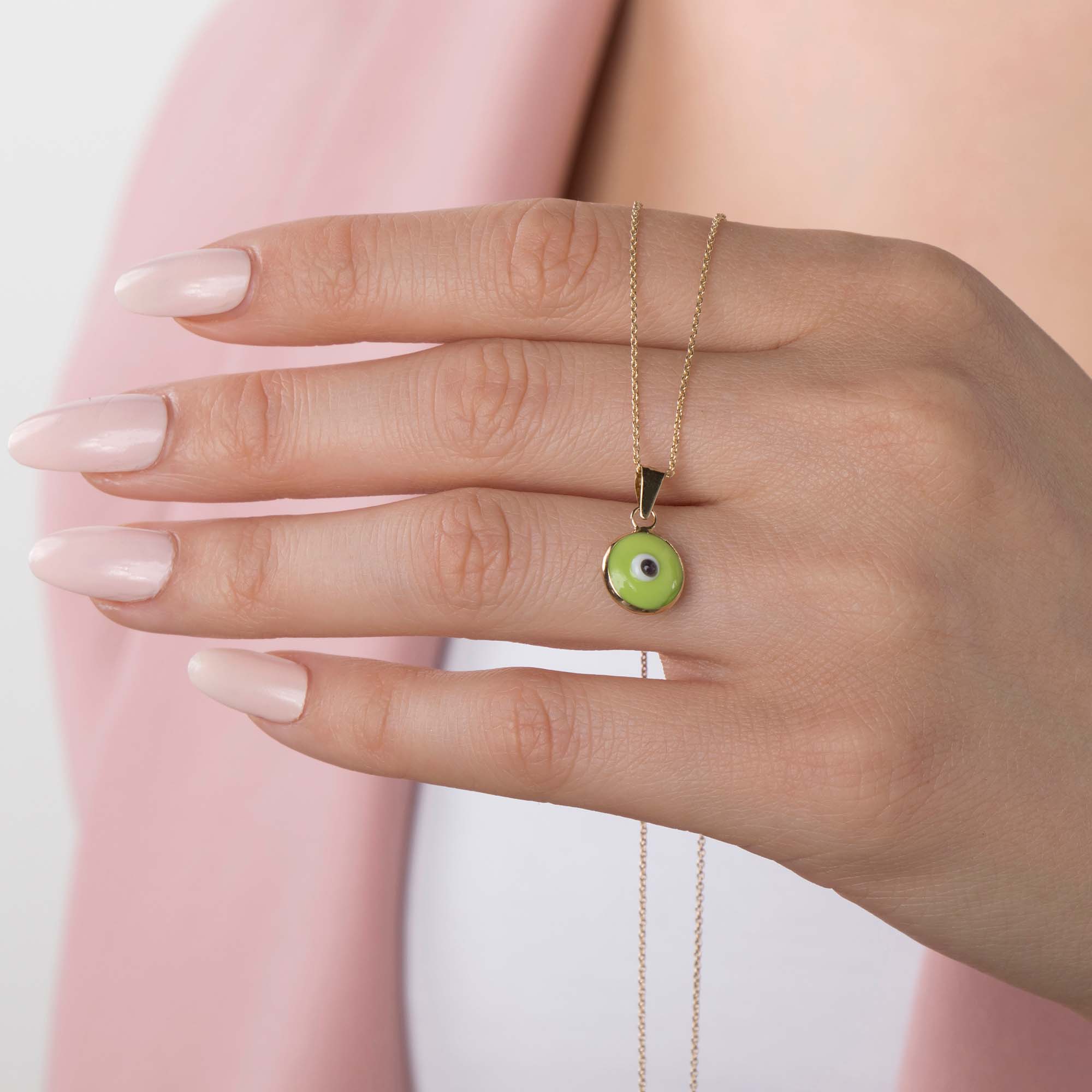 A model wearing a lime green evil eye pendant on a thin gold chain