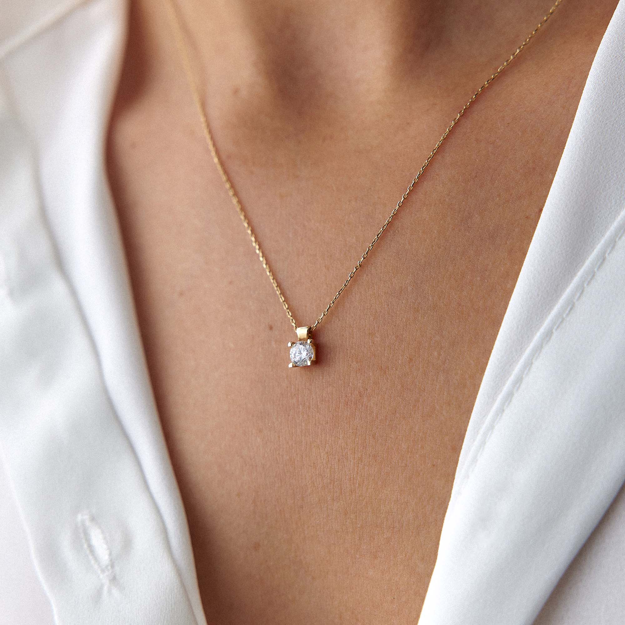A model wearing a solitaire necklace shown up-close.