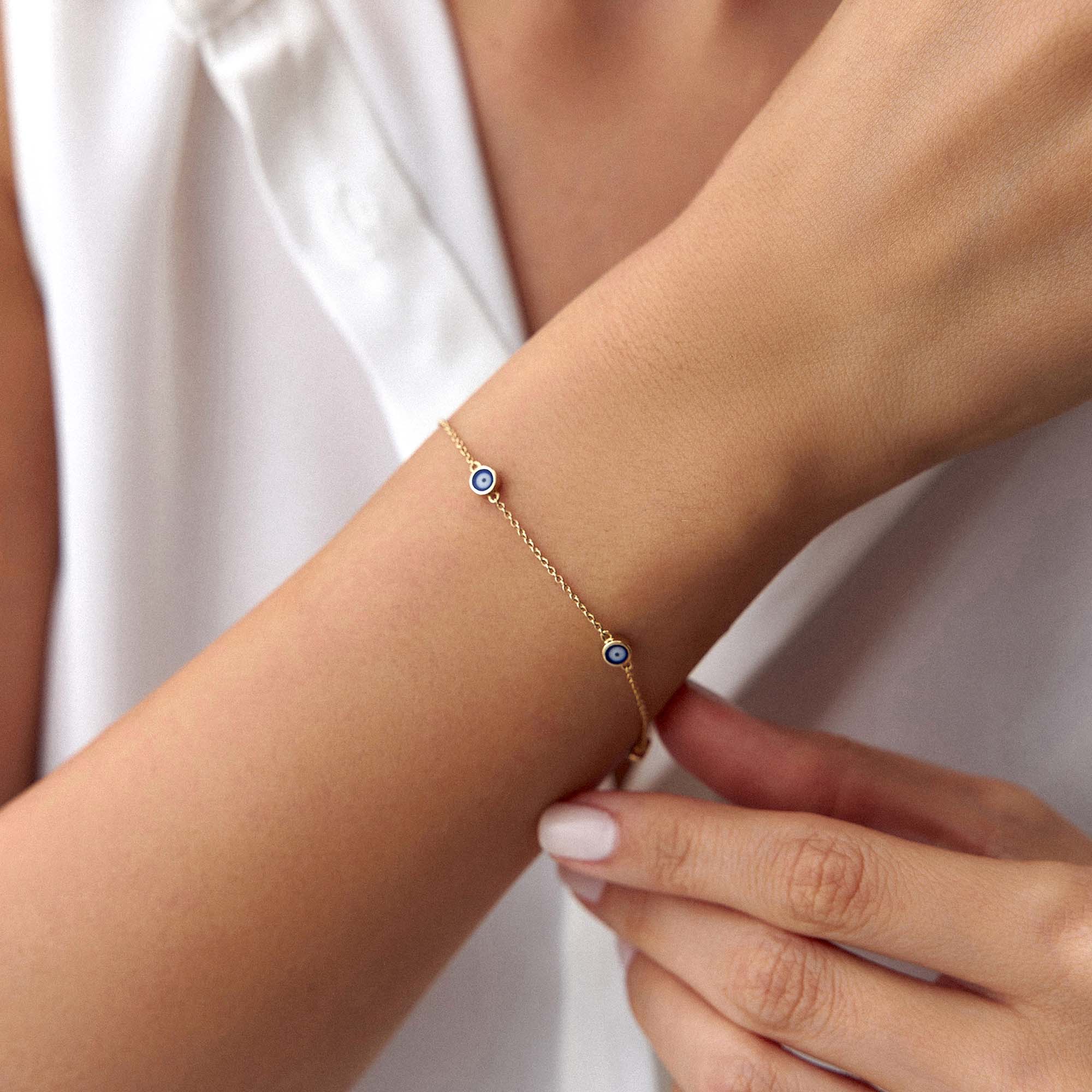 14k yellow gold navy blue evil eye bracelet with 5 evil eyes shown on a wrist