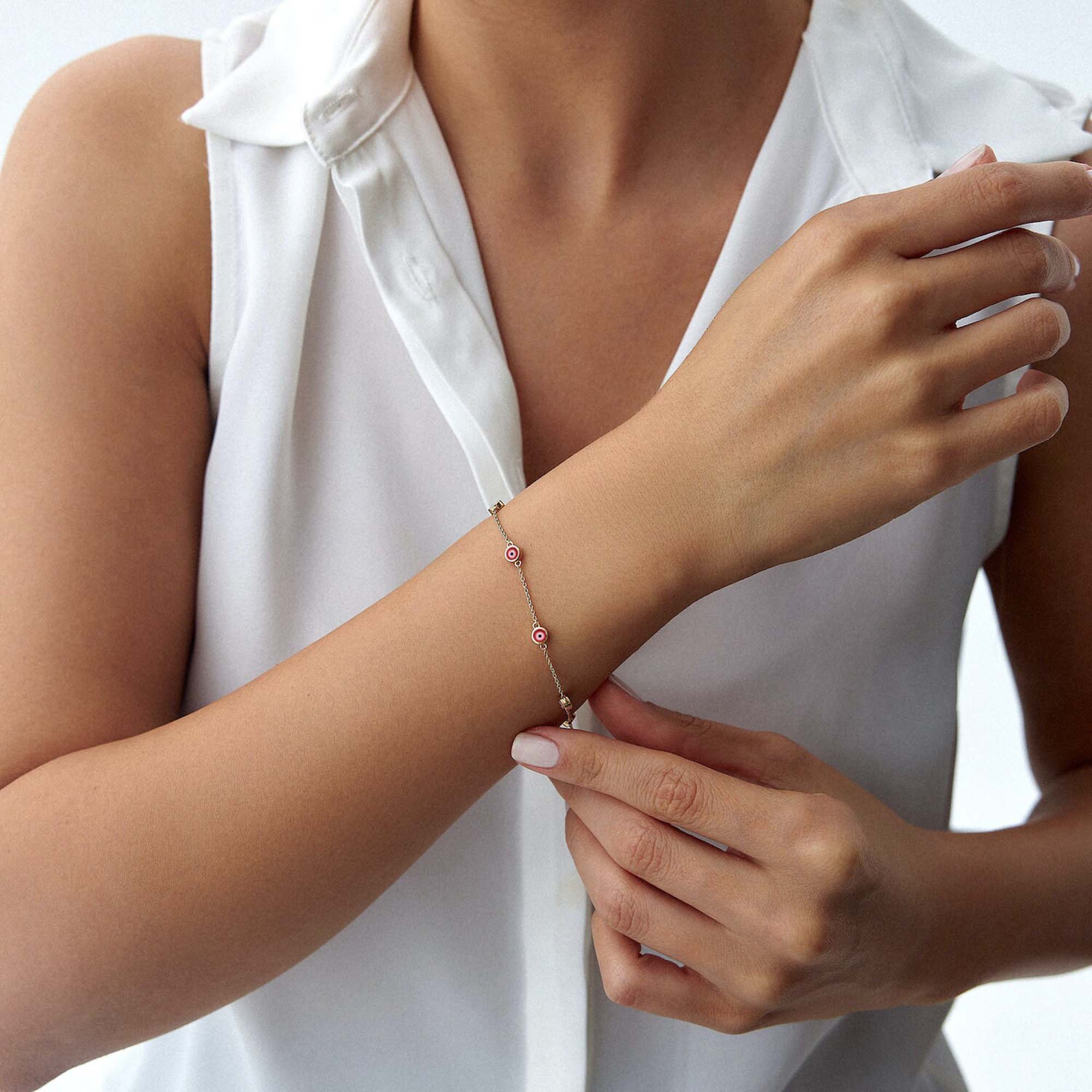 14k yellow gold red evil eye bracelet with 7 evil eyes shown on a wrist