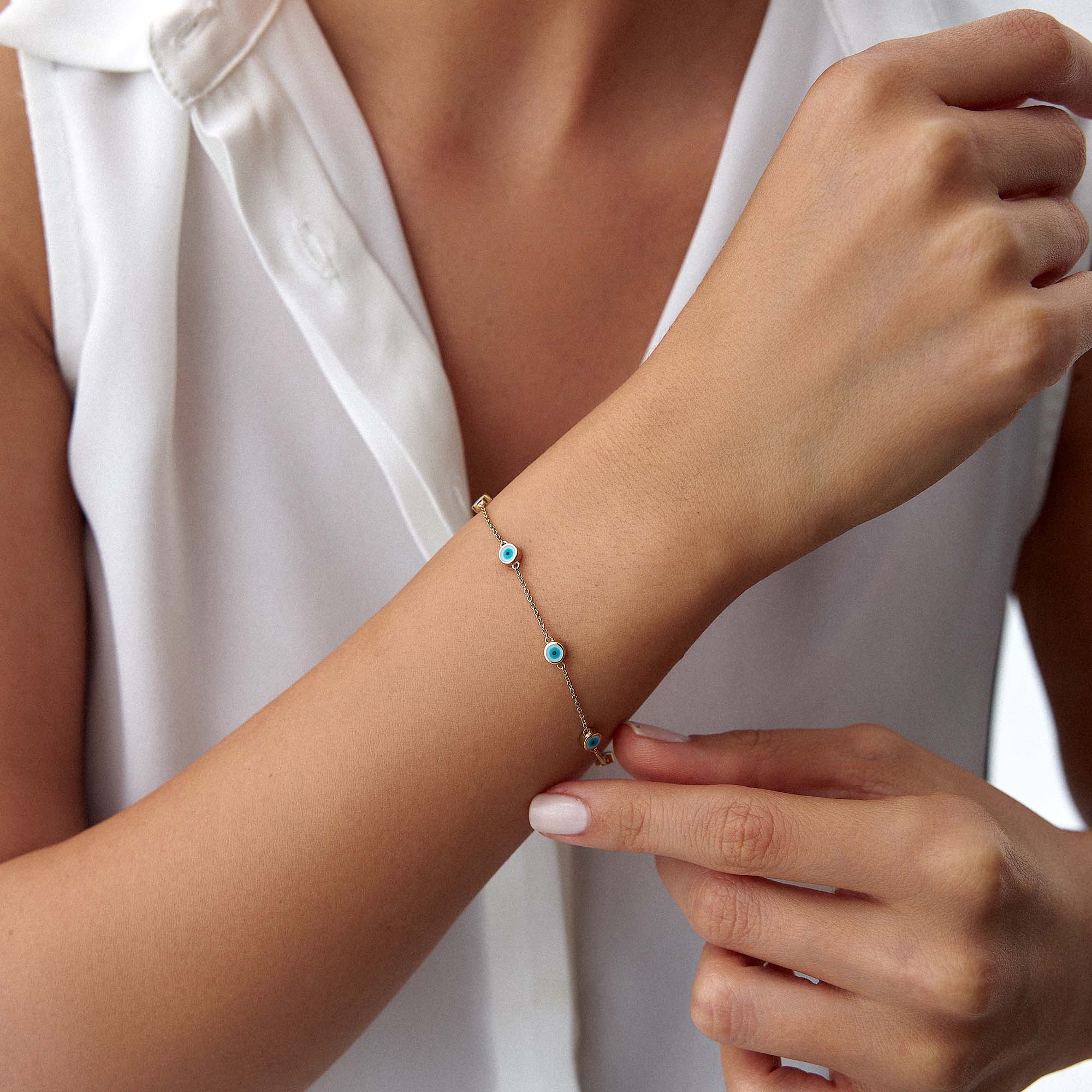 14k yellow gold evil eye bracelet with 7 white evil eyes shown on a wrist