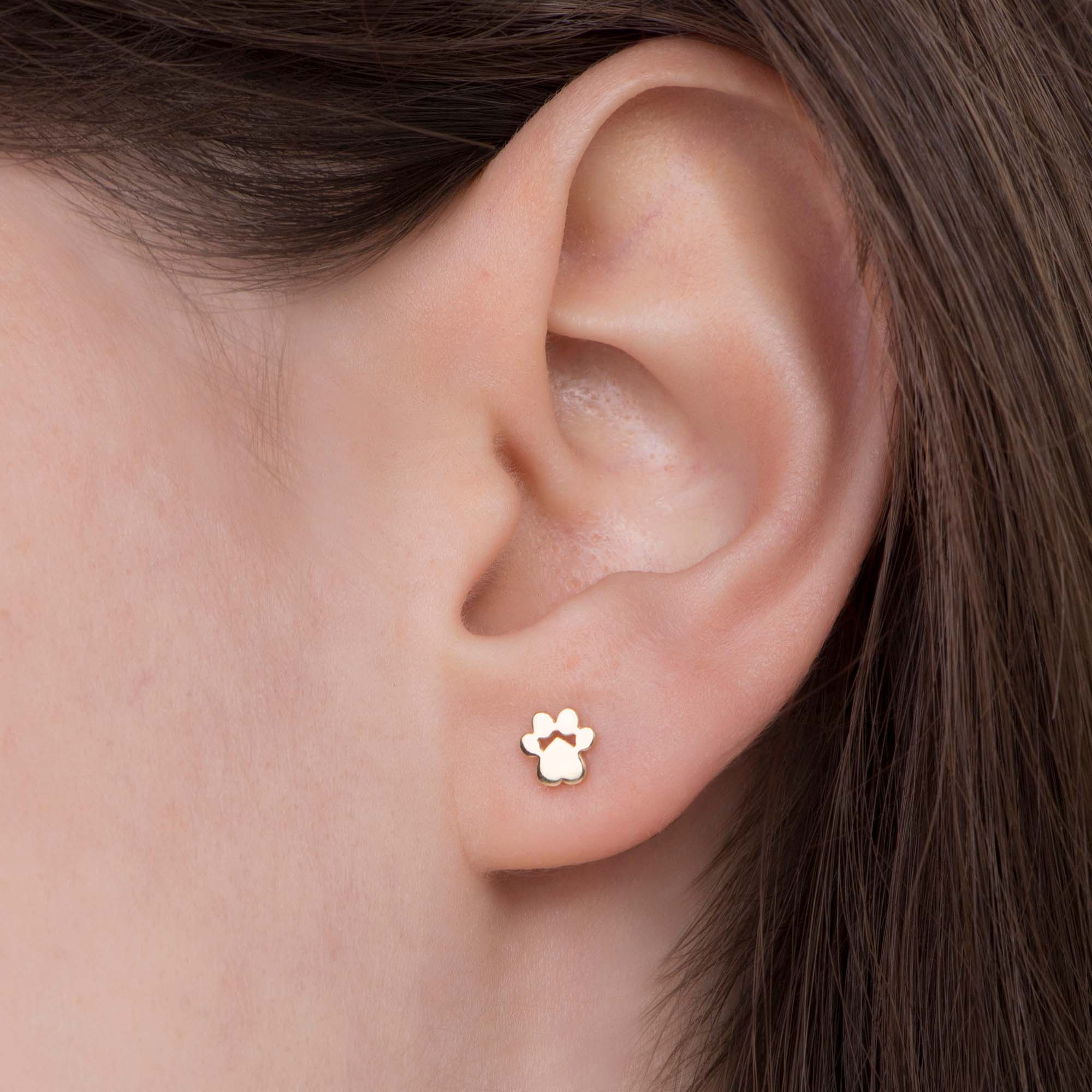 14k yellow gold mini paw stud shown on an ear