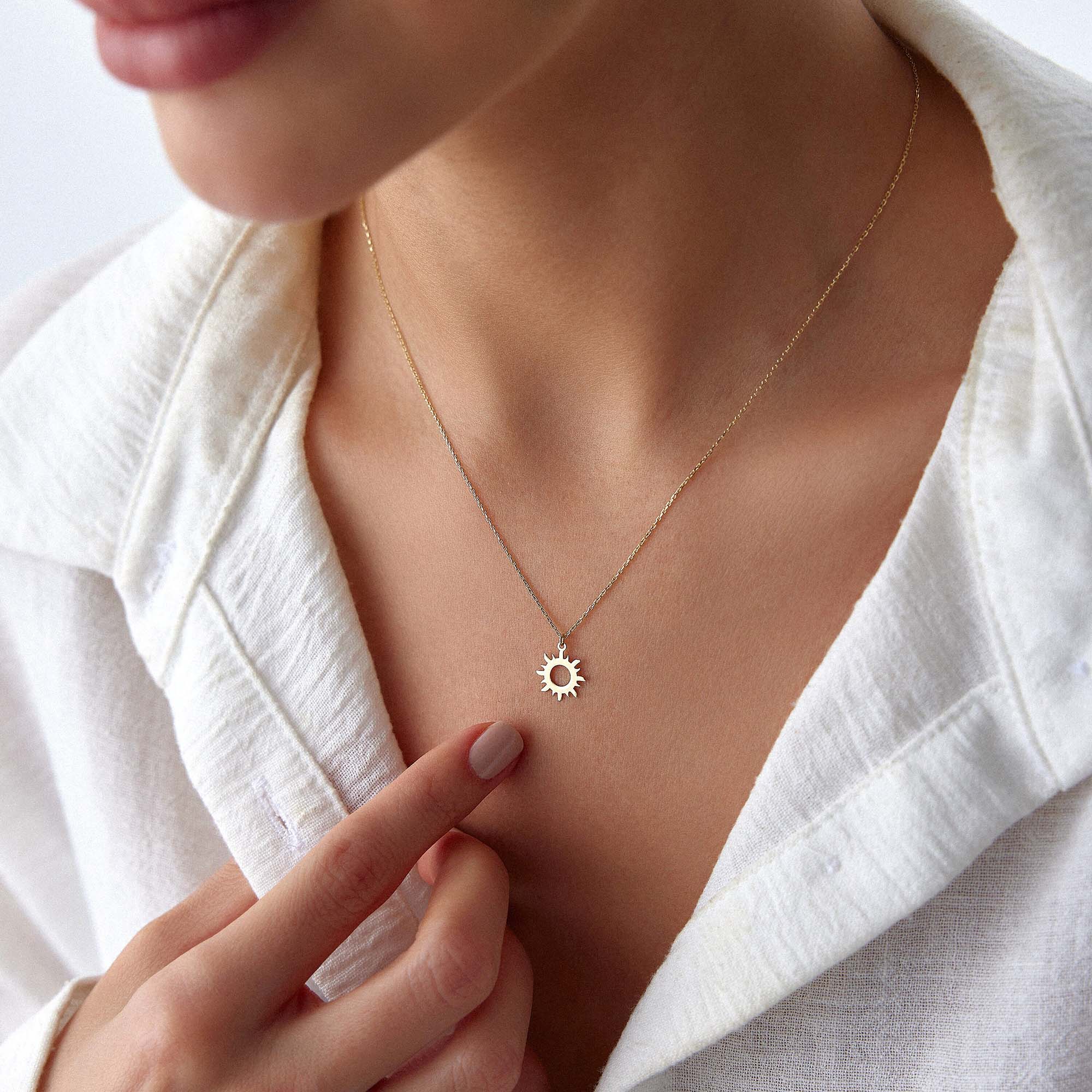 An image of a model wearing a minimal sun pendant necklace.