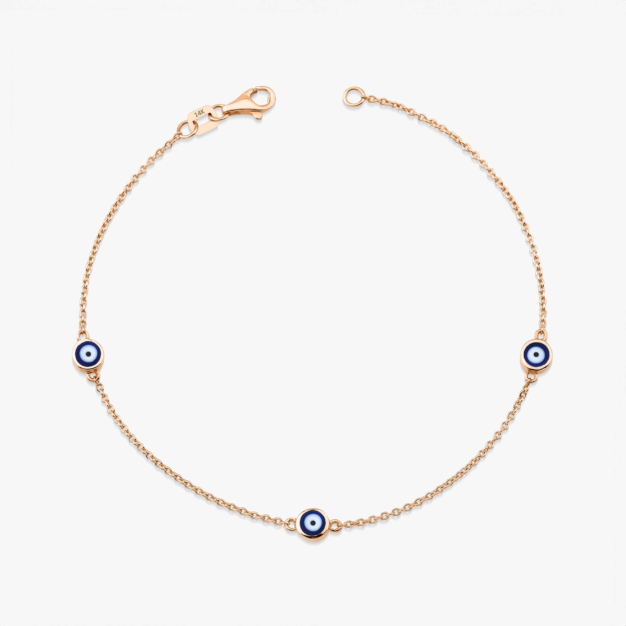 A 14 karat yellow gold bracelet with three navy blue evil eye charms on a white background