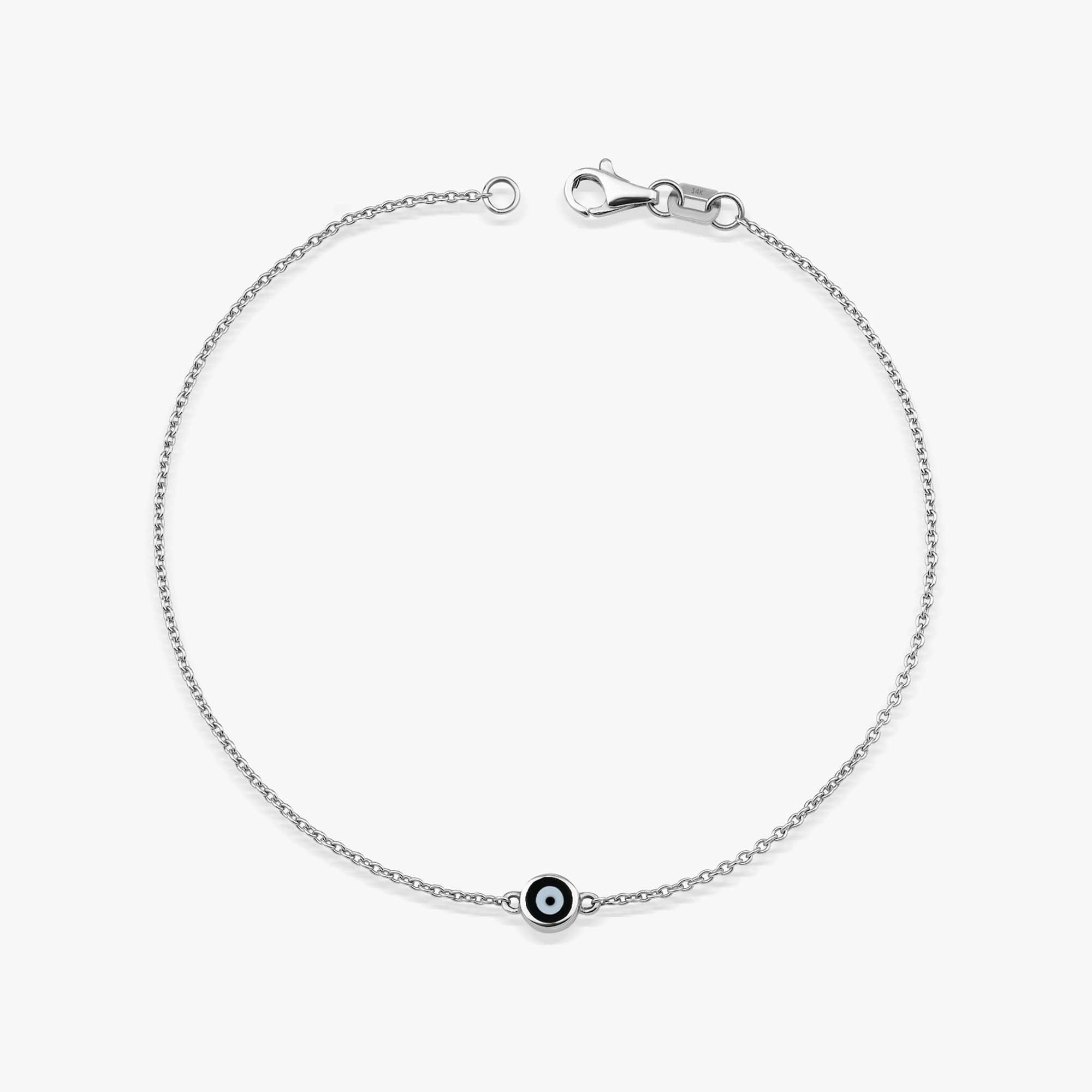 A 14K solid white gold evil eye bracelet with a minimal black enamel design on a white background.