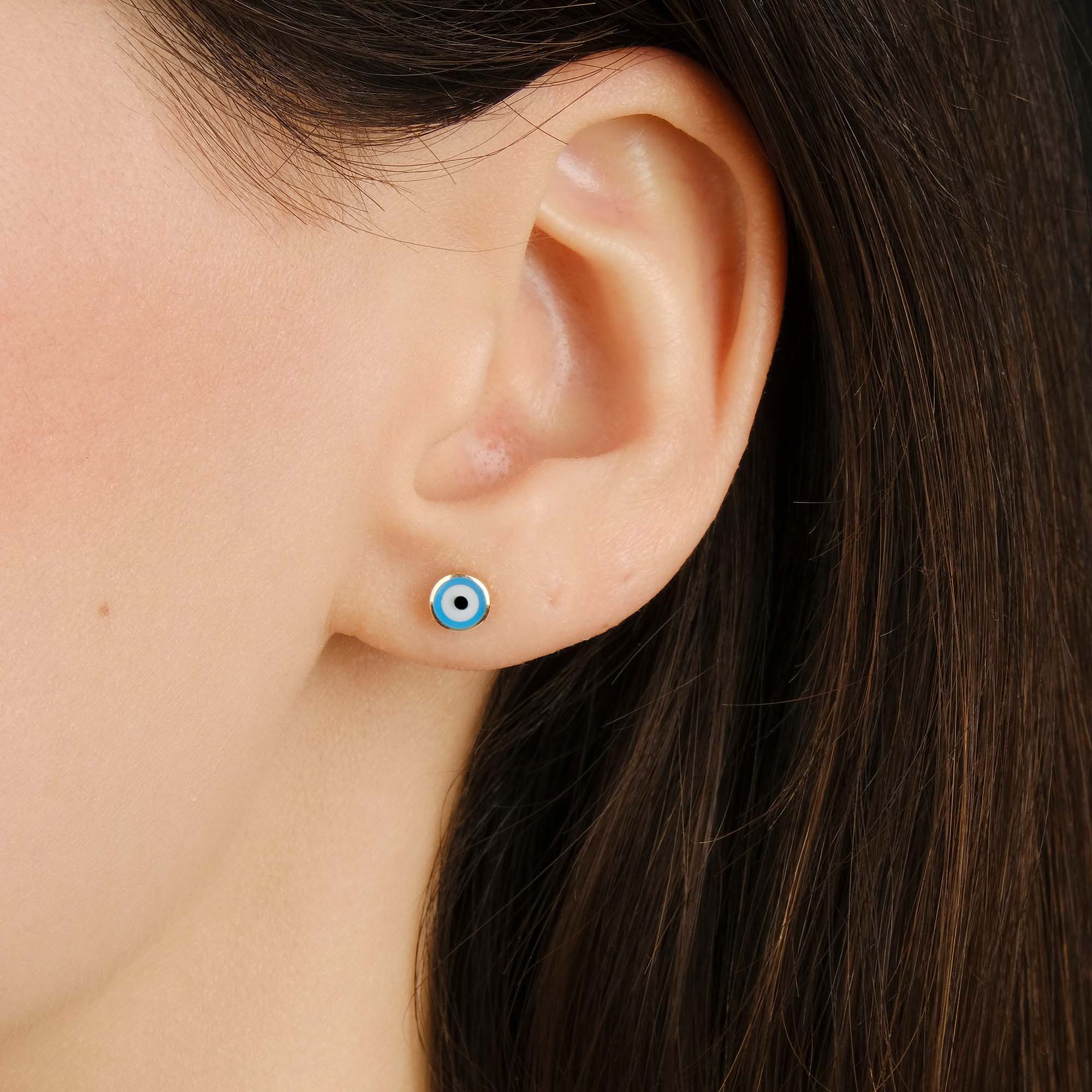 Close-up of an ear with a tiny ocean blue evil eye stud.