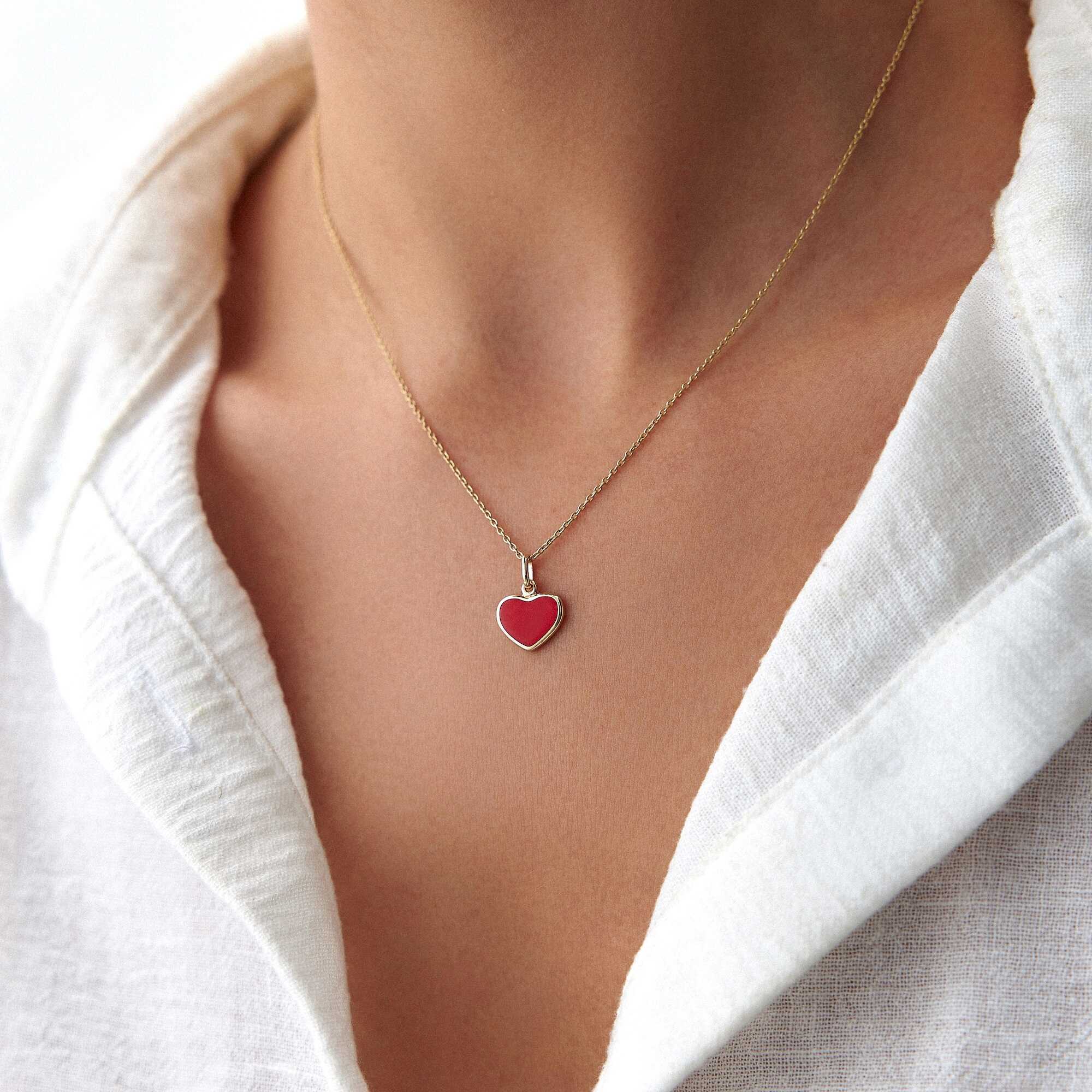 A model wearing a 14k yellow gold red enamel heart pendant worn on a thin gold chain