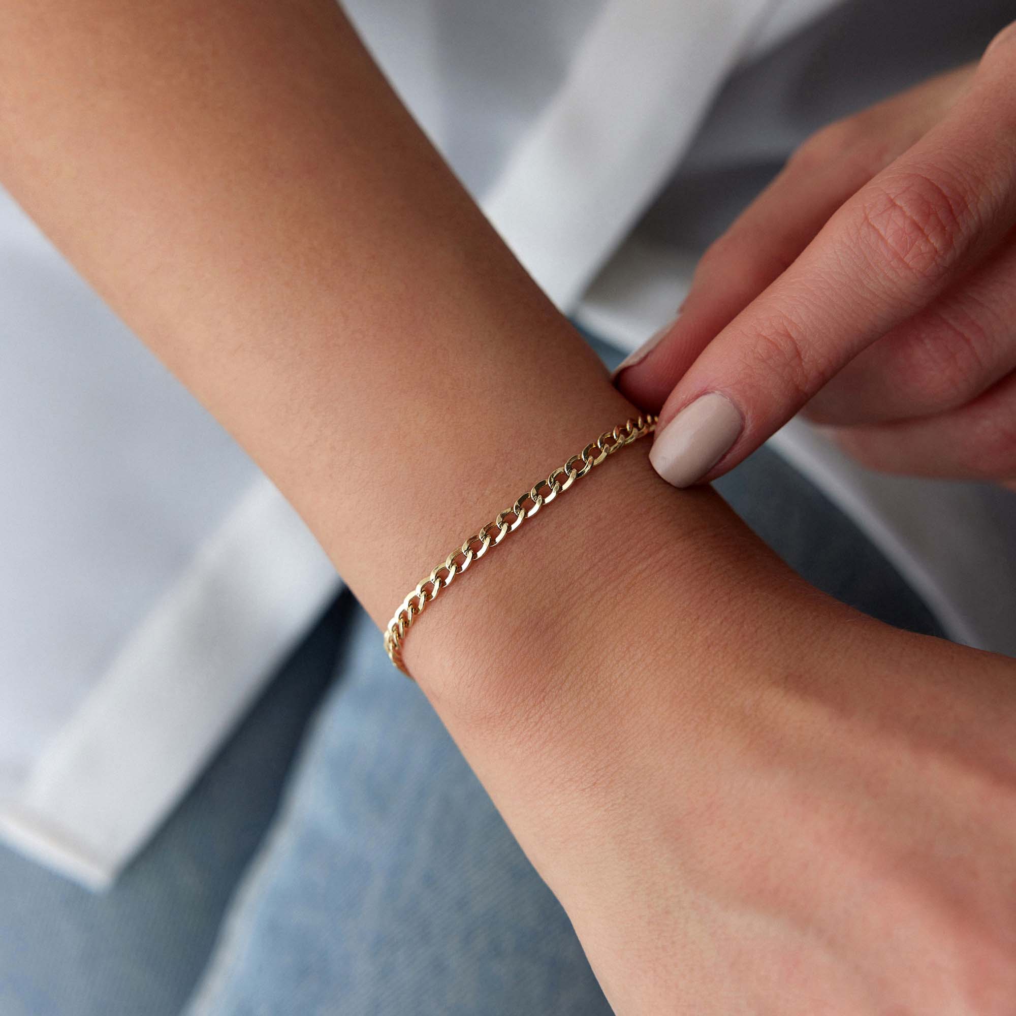 Minimal Gold curb chain bracelet on a wrist with a neutral background