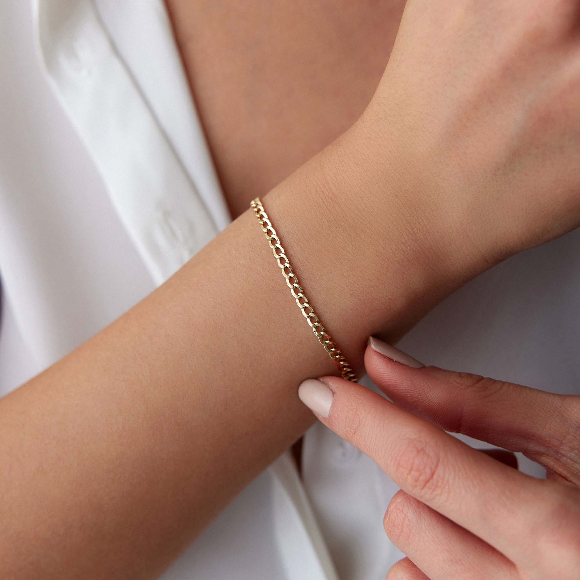 Mimal Gold curb bracelet on a wrist with a neutral background