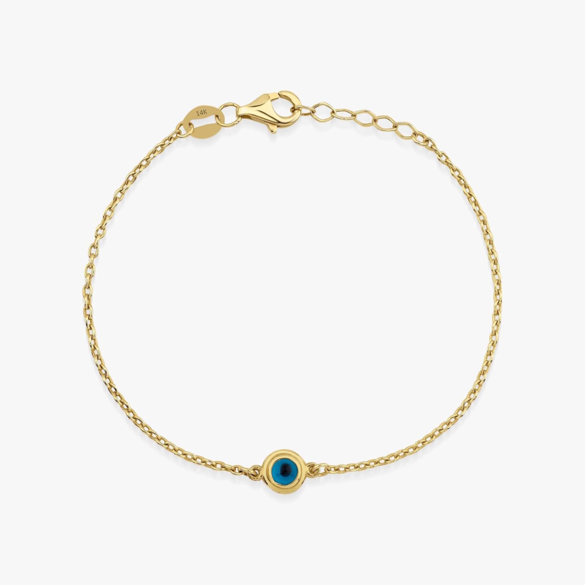 Gold bracelet with a blue eye charm on a white background