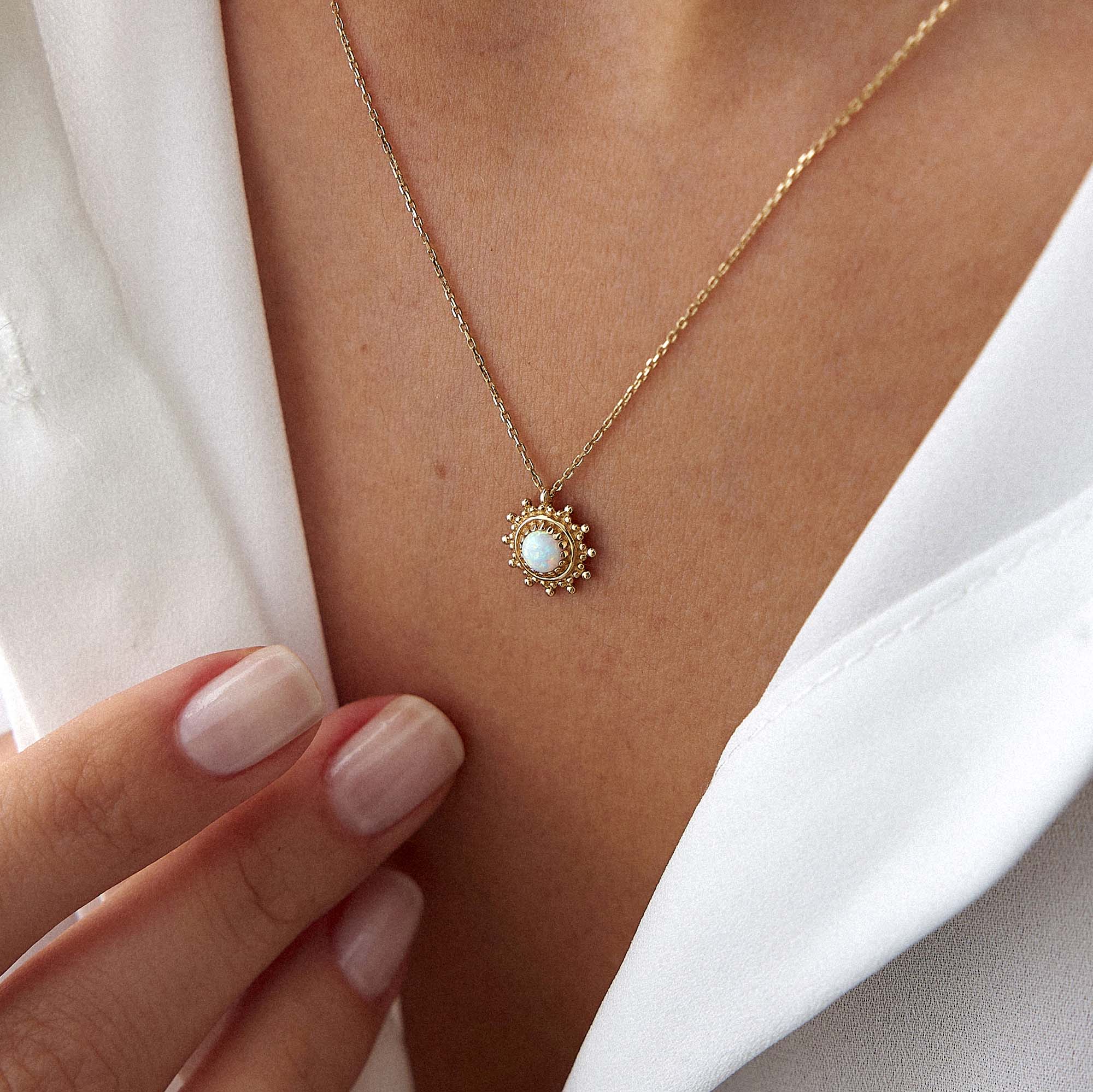 A model wearing a minimal sun necklace with a lab opal center shown upclose