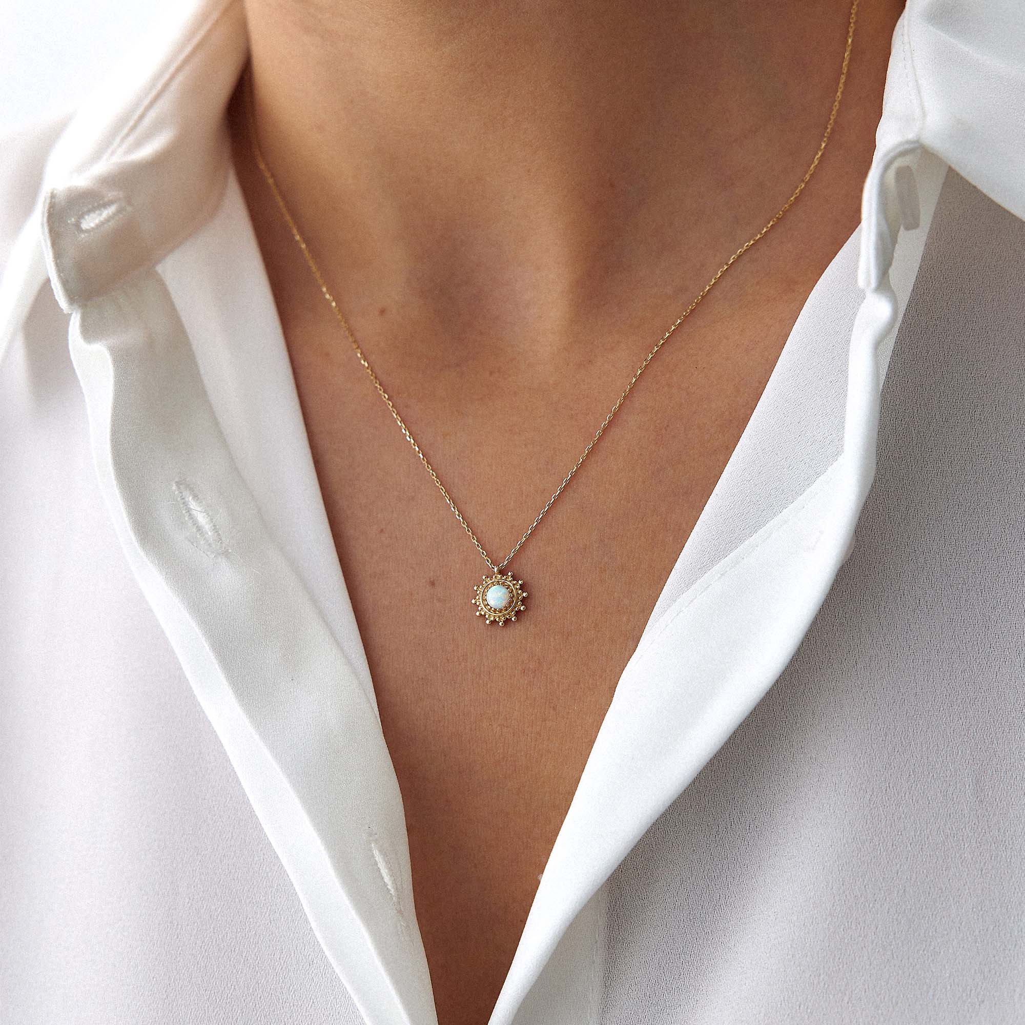 A model wearing a minimal sun necklace with a lab opal center shown upclose