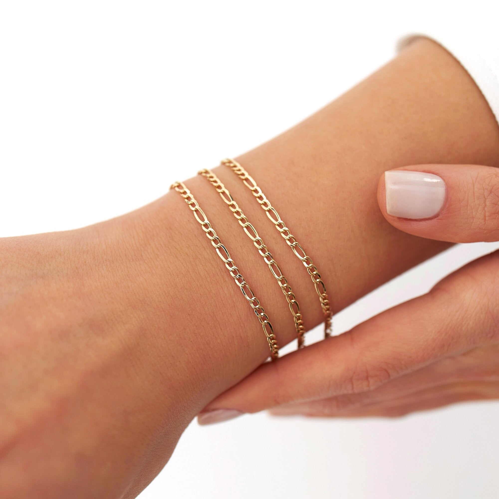 Three minimal figaro chain bracelets on a models wrist