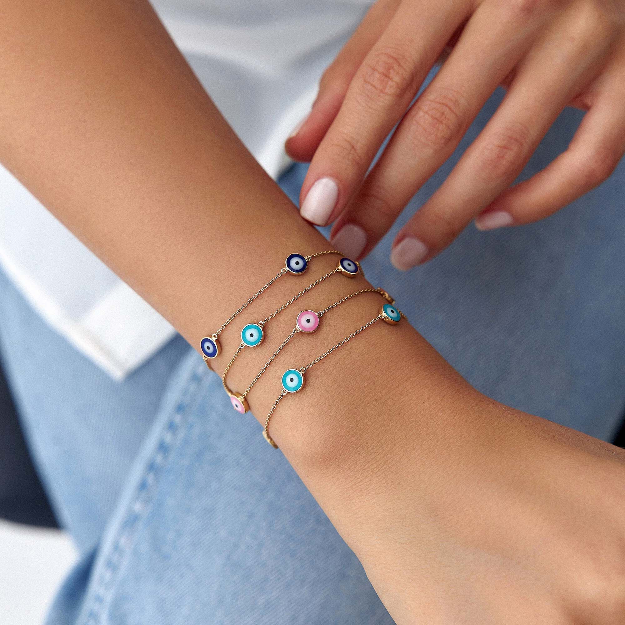 Close-up of a wrist wearing multiple colorful bracelets with eye designs.