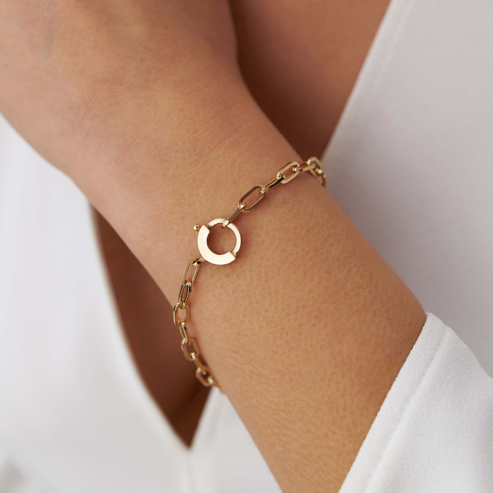 14k yellow gold paperclip chain bracelet with a special circular clasp shown on a wrist