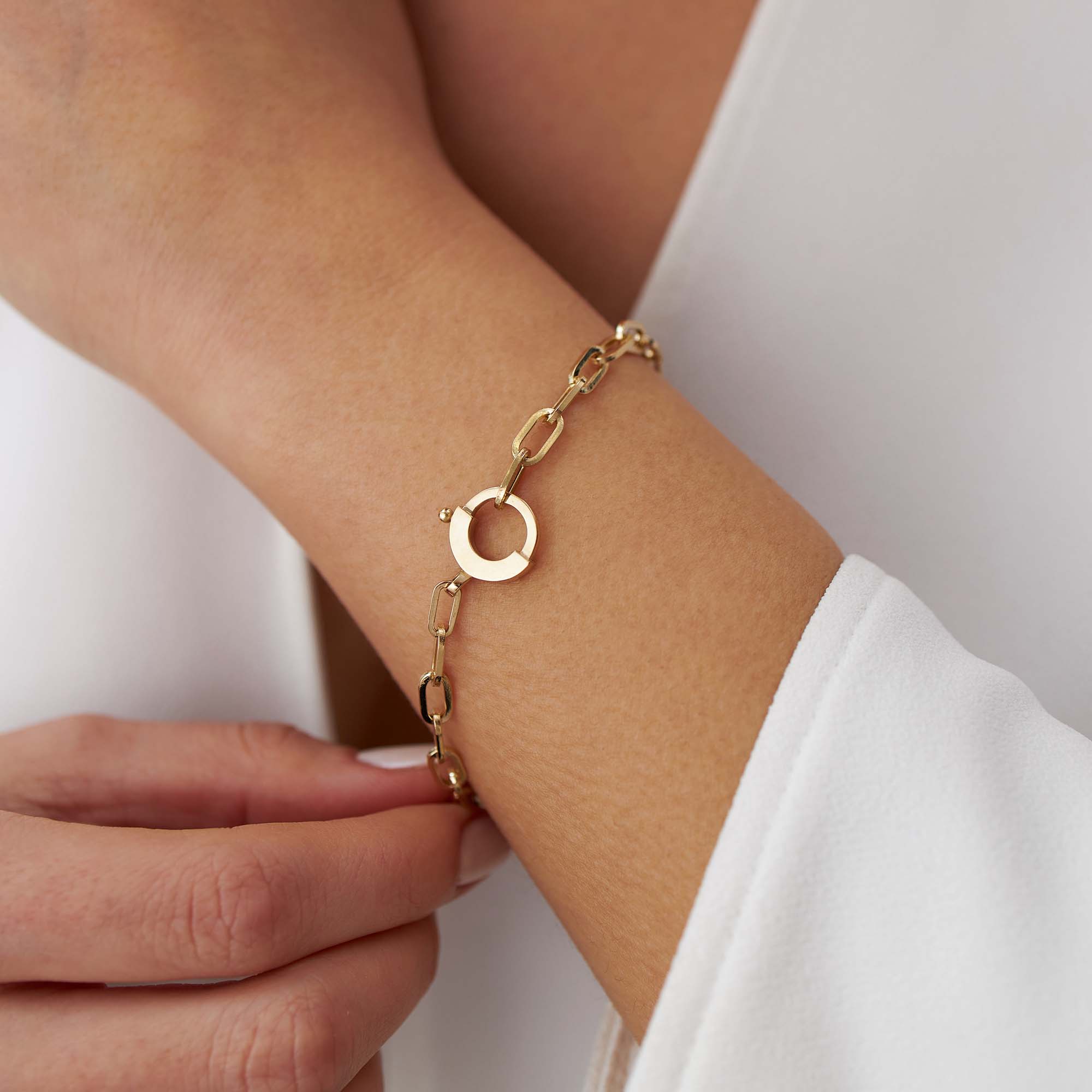 14k yellow gold paperclip chain bracelet with a special circular clasp shown on a wrist