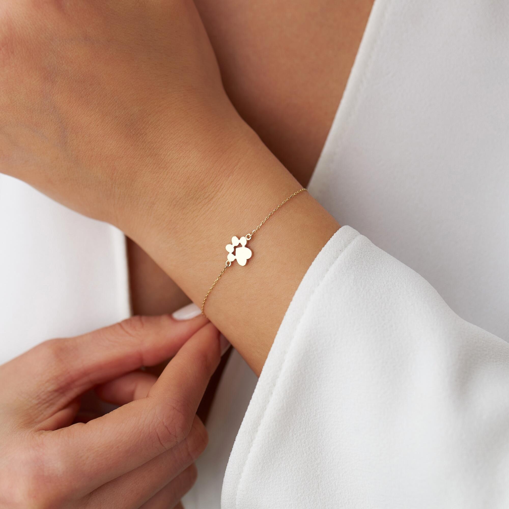 Model wearing a small gold paw bracelet