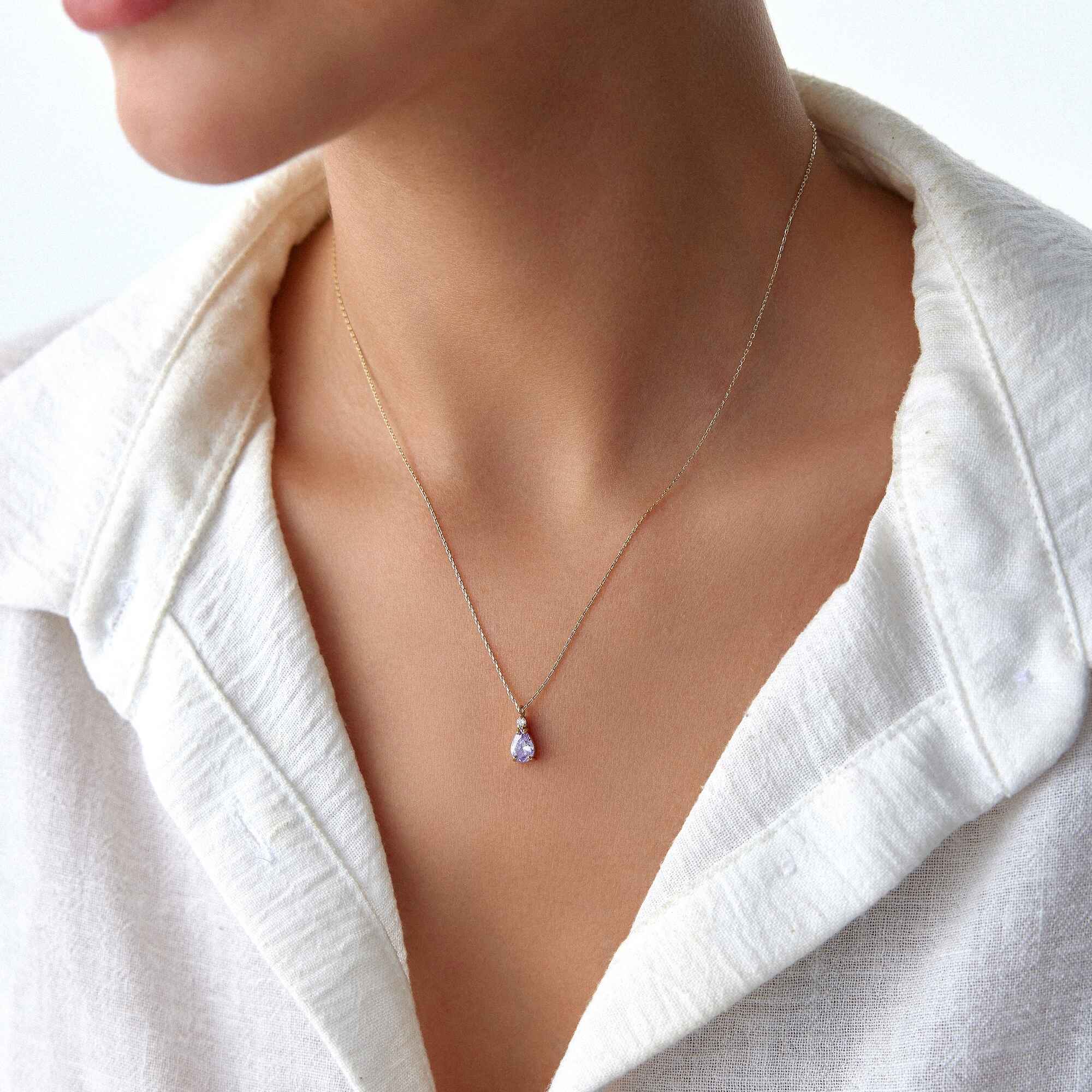 A model wearing a 14k yellow gold purple necklace.