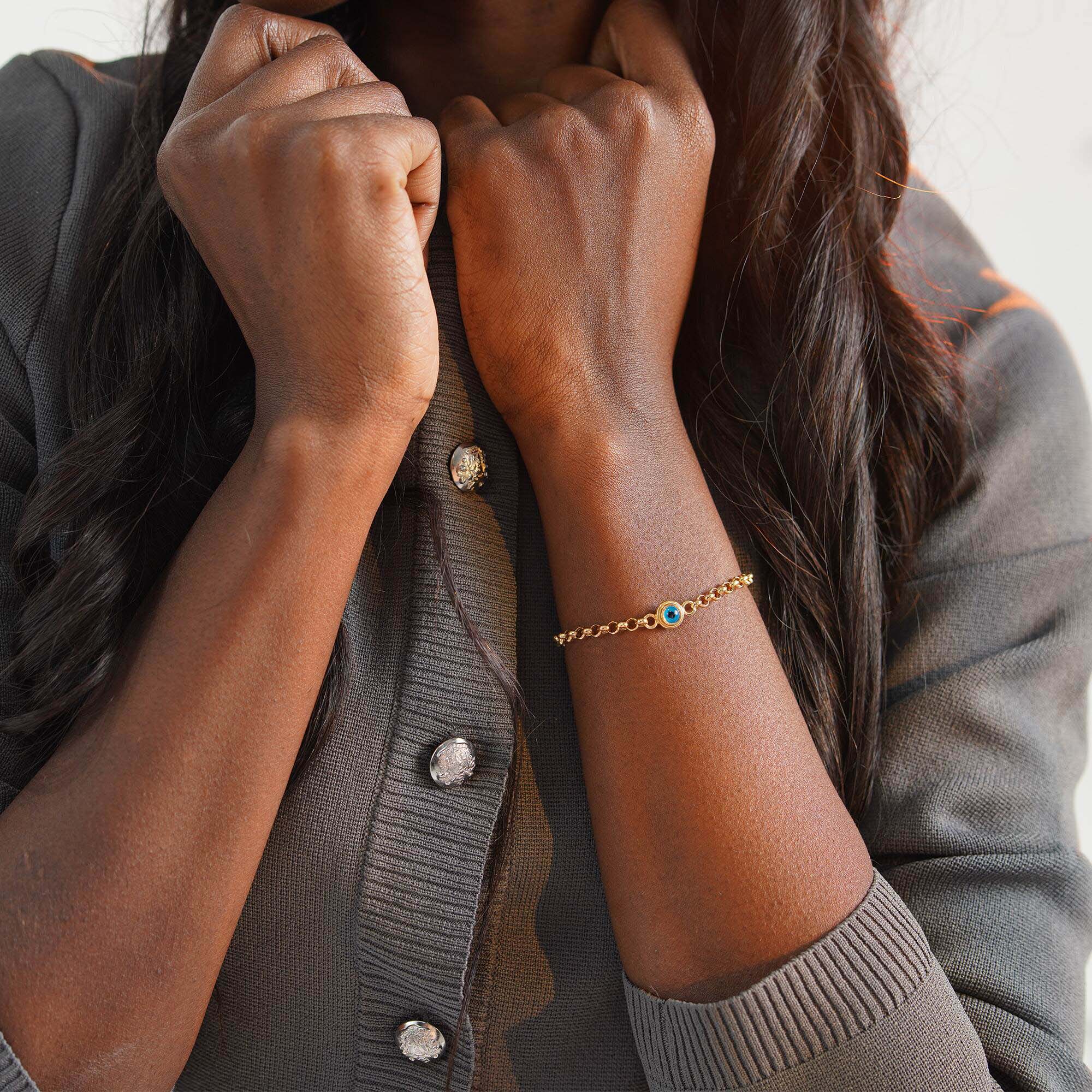 Close-up of a person wearing a gold evil eye bracelet