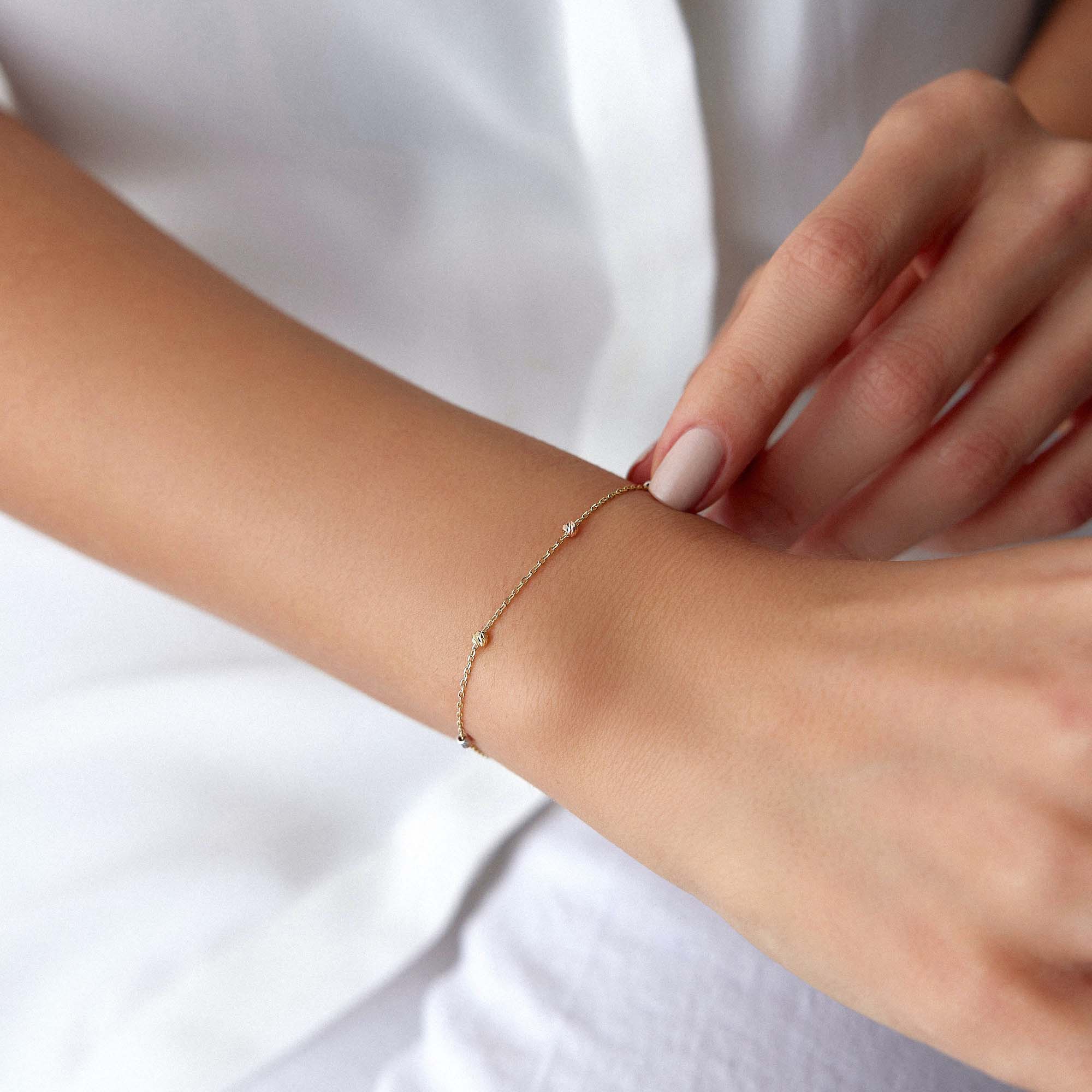 14k yellow gold tricolor beaded chain bracelet shown on a wrist