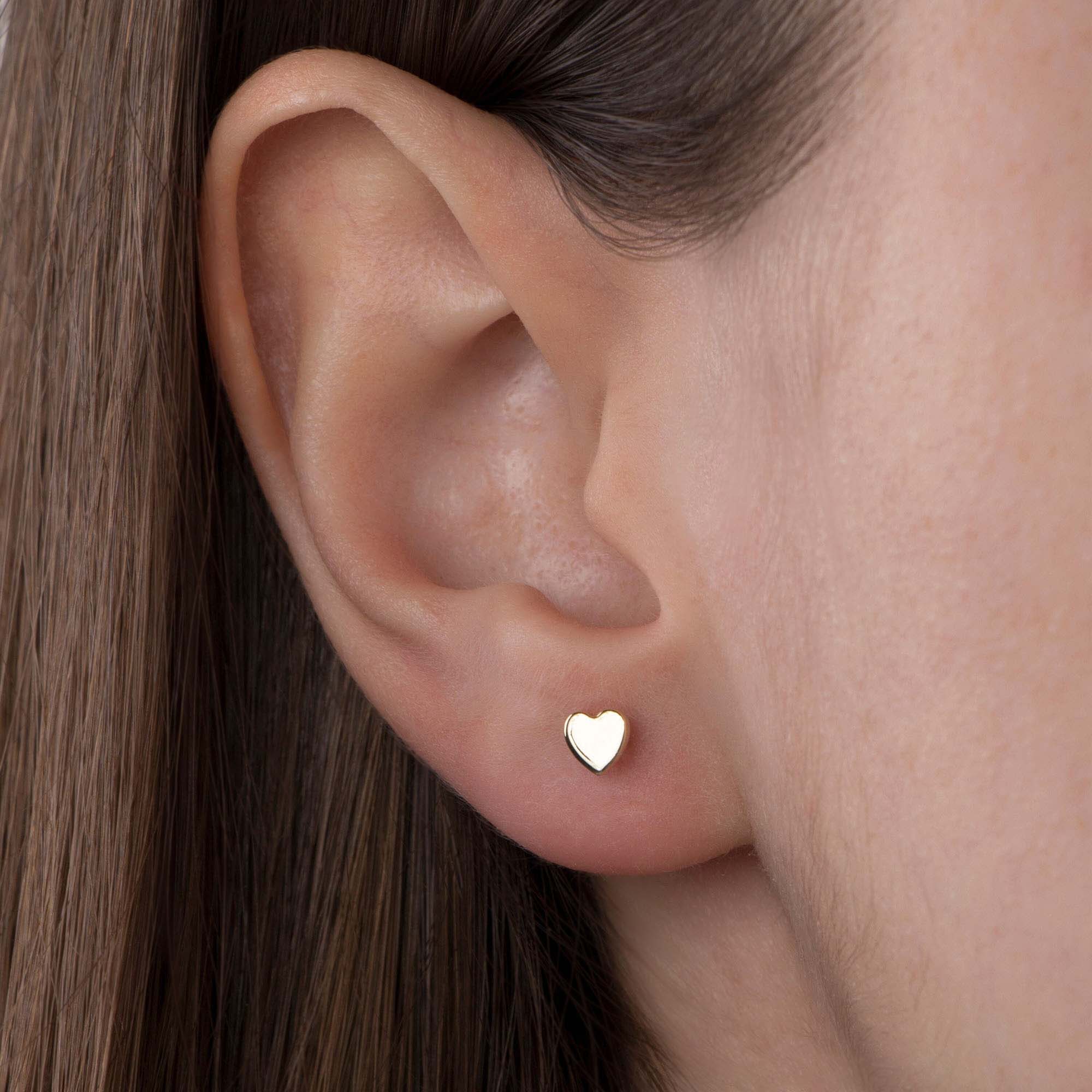 Heart-shaped stud worn on an ear with a neutral background