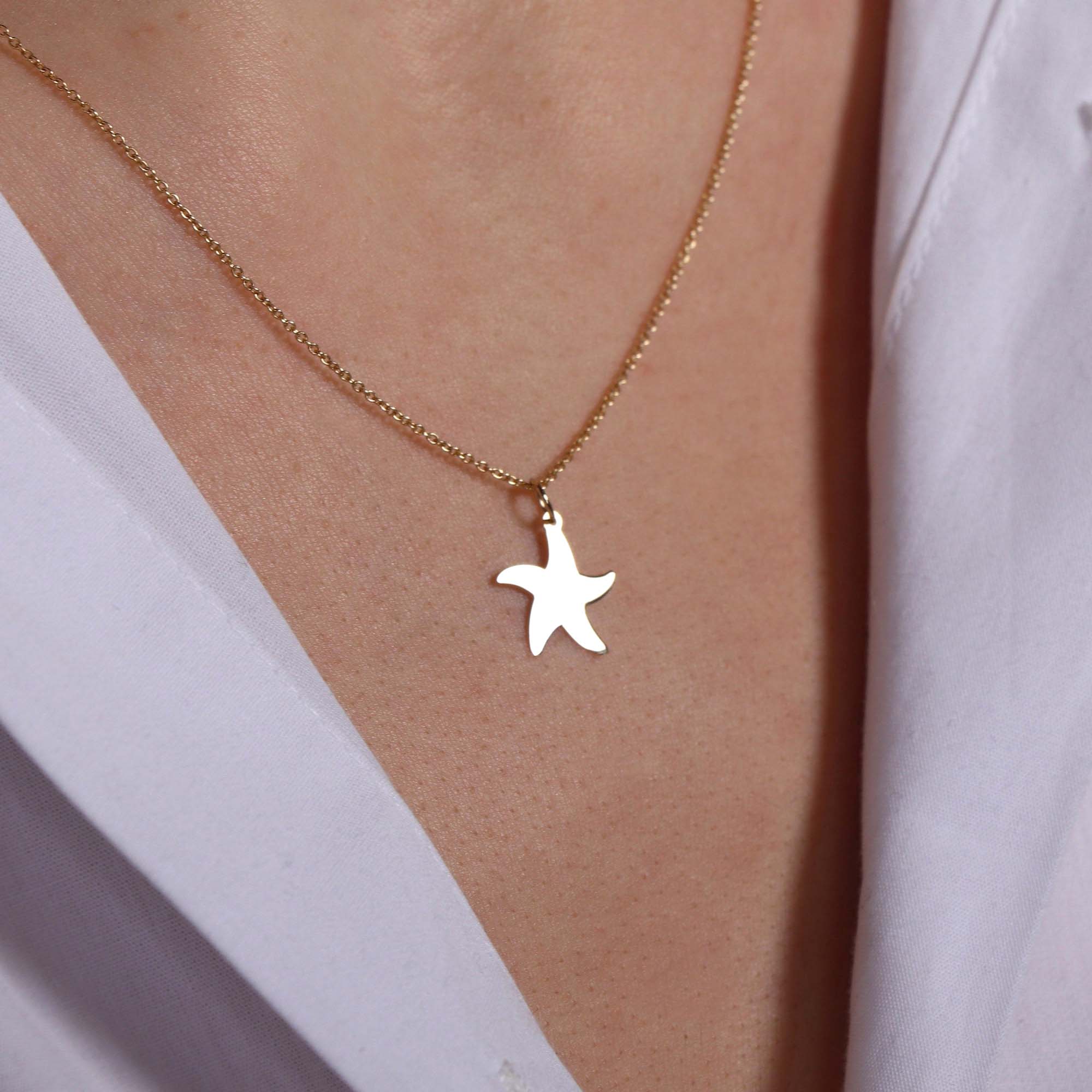 Starfish pendant necklace on a person's neck with a light background