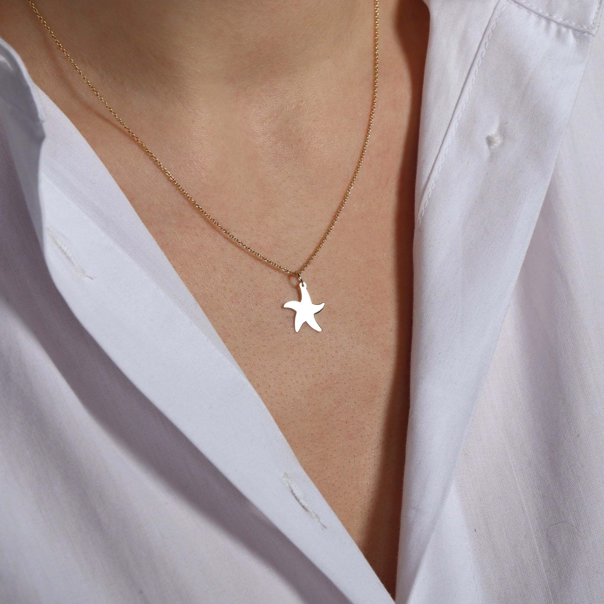 Starfish pendant necklace on a person's neck with a light background