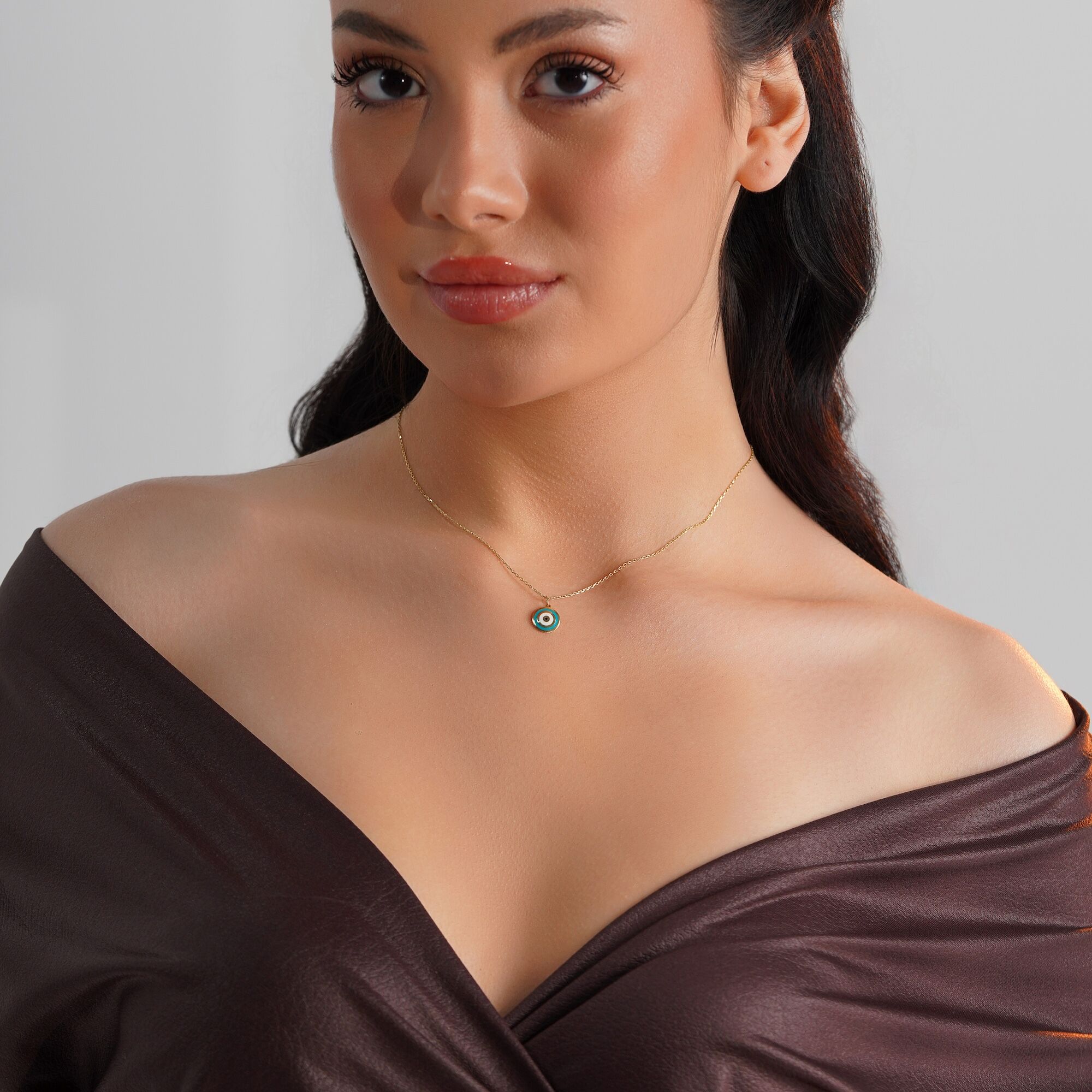 A model wearing an turquoise evil eye pendant on a thin gold chain.