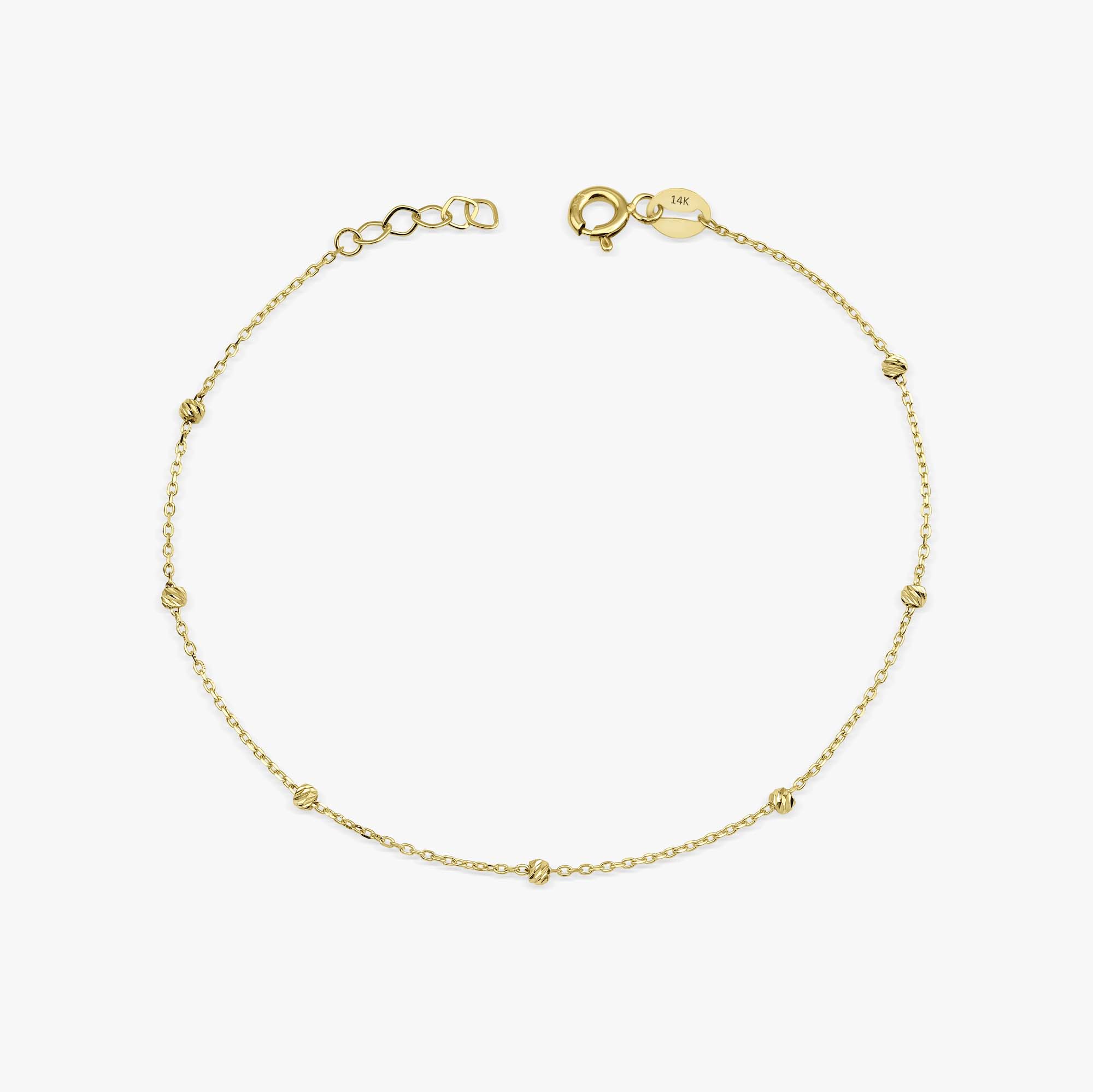 A delicate gold bracelet with small beads strung on a chain, fastened with a gold clasp.