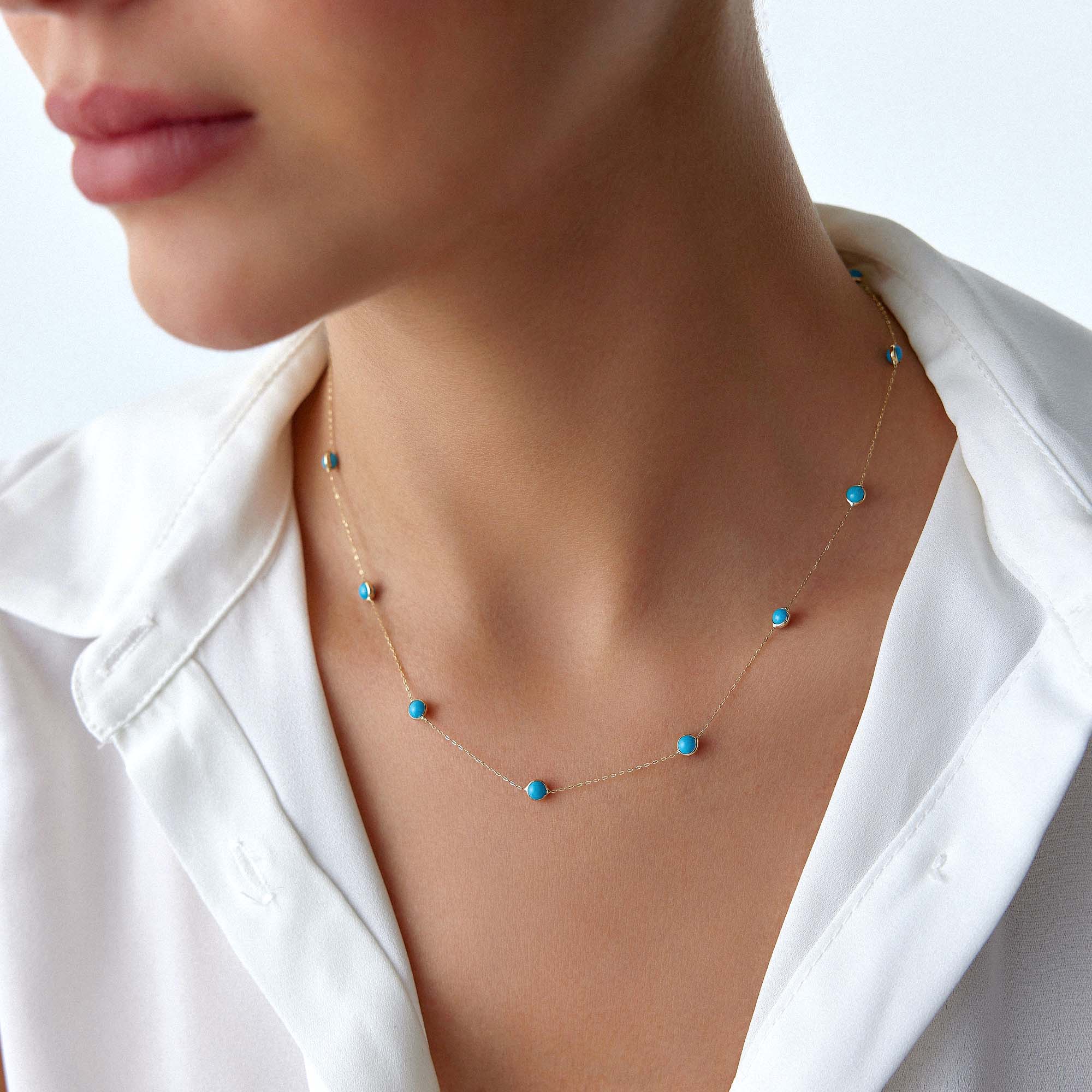 Necklace with turquoise beads worn by a person in a white shirt