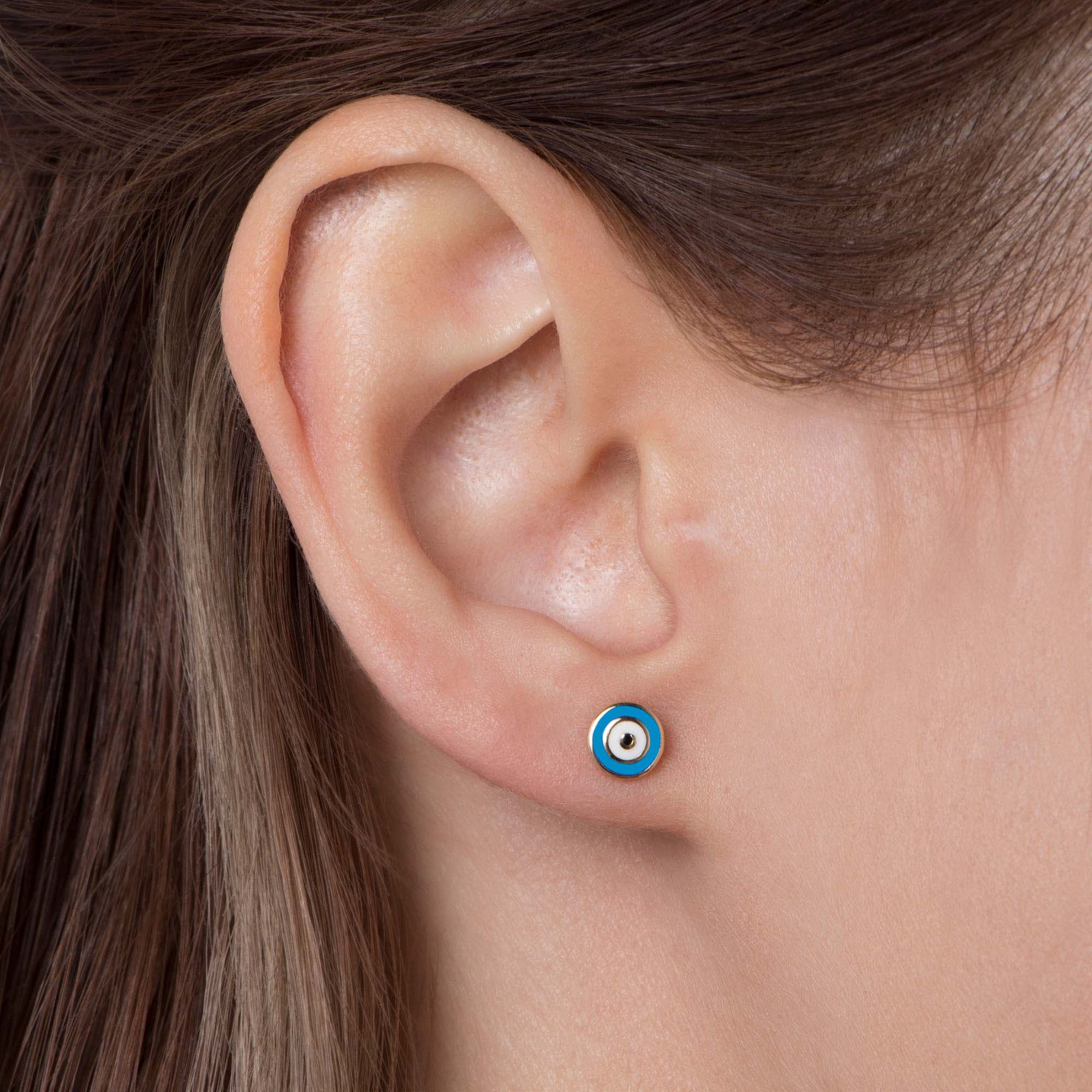 Close-up of an ear wearing a turquoise evil eye stud.