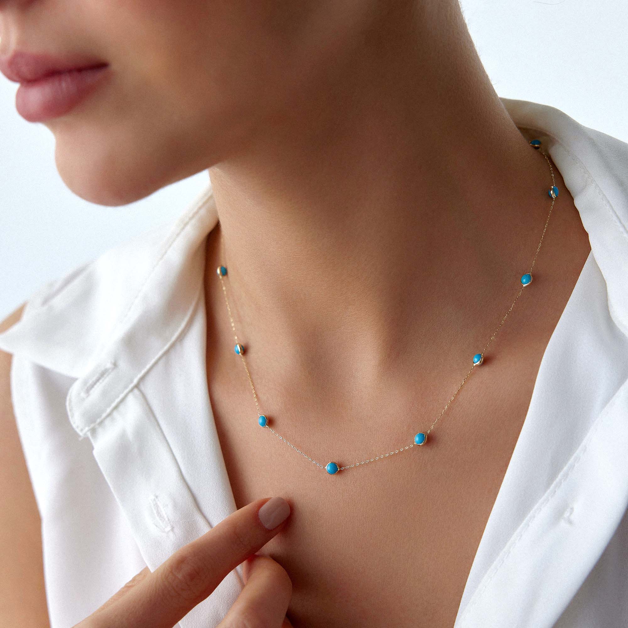 Necklace with turquoise beads worn by a person in a white shirt