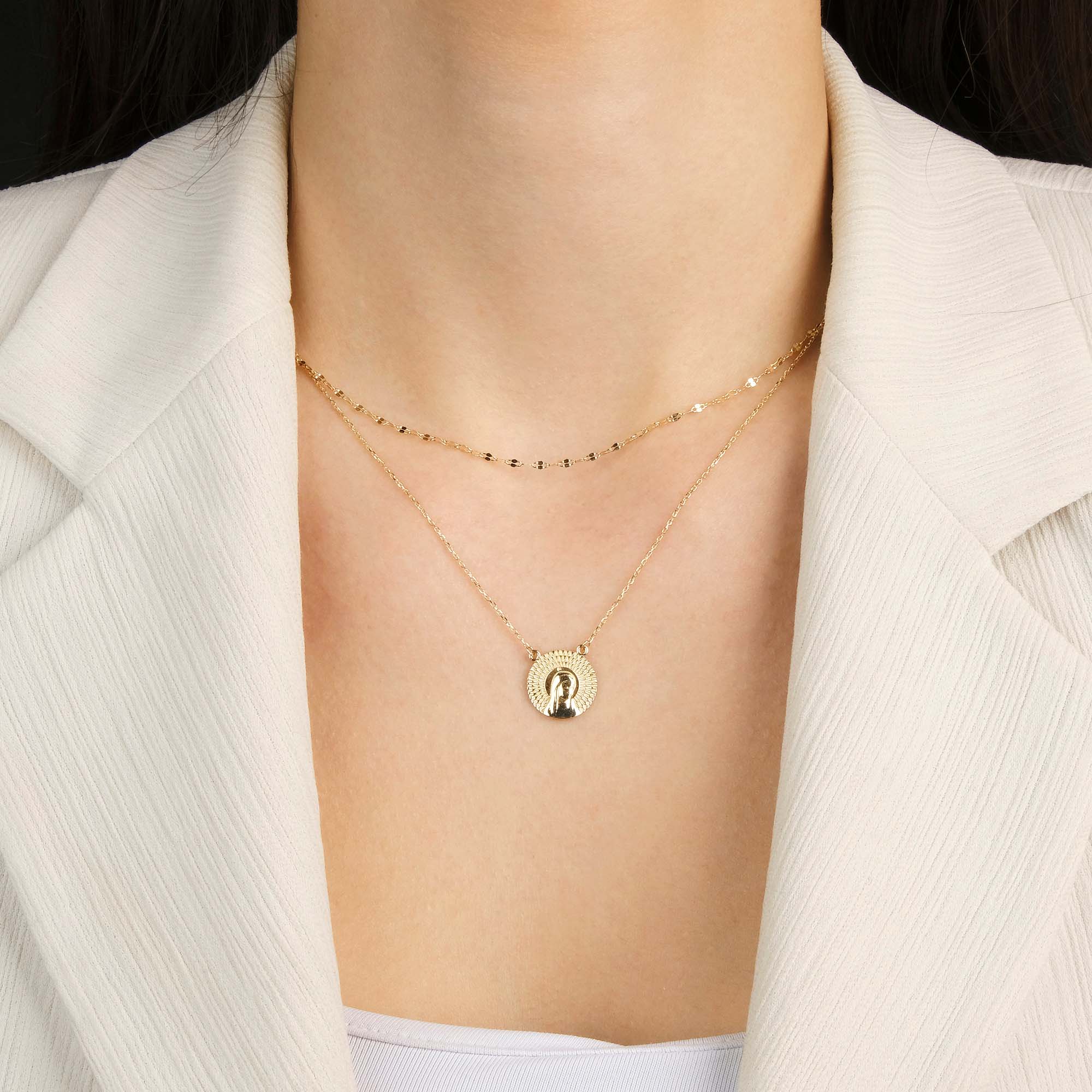 A model wearing a virgin mary necklace with an italian sparkle chain to layer it.