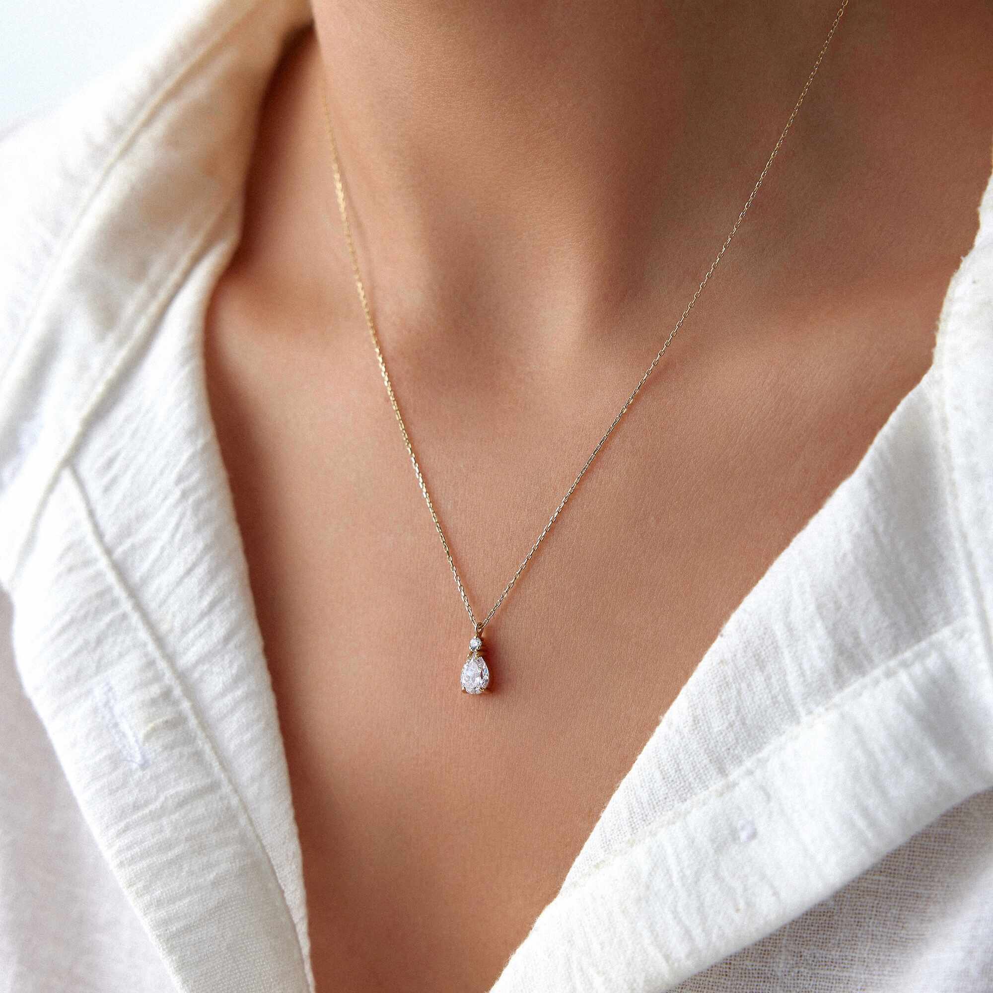 A 14k yellow gold white drop necklace worn by a model