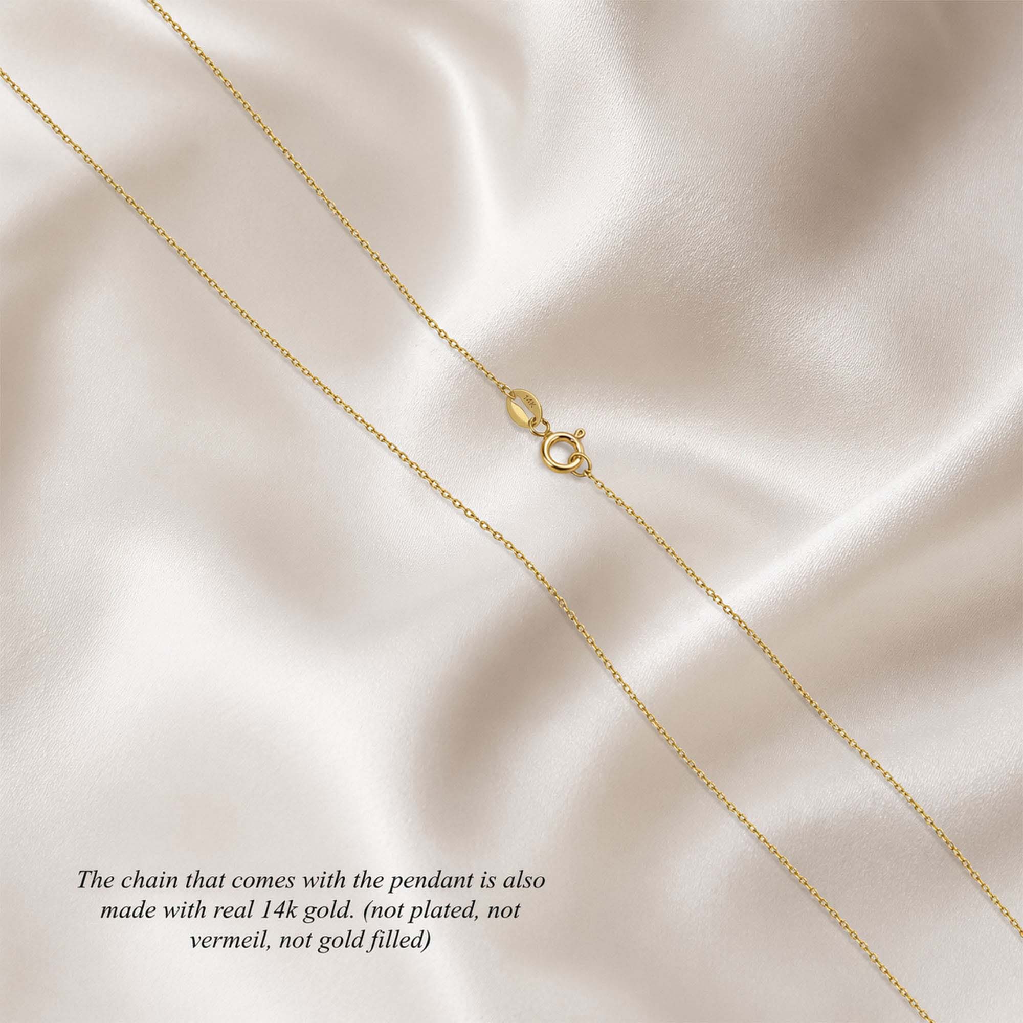 A 14k solid gold cable chain with a spring clasp on a soft, light-colored fabric background.