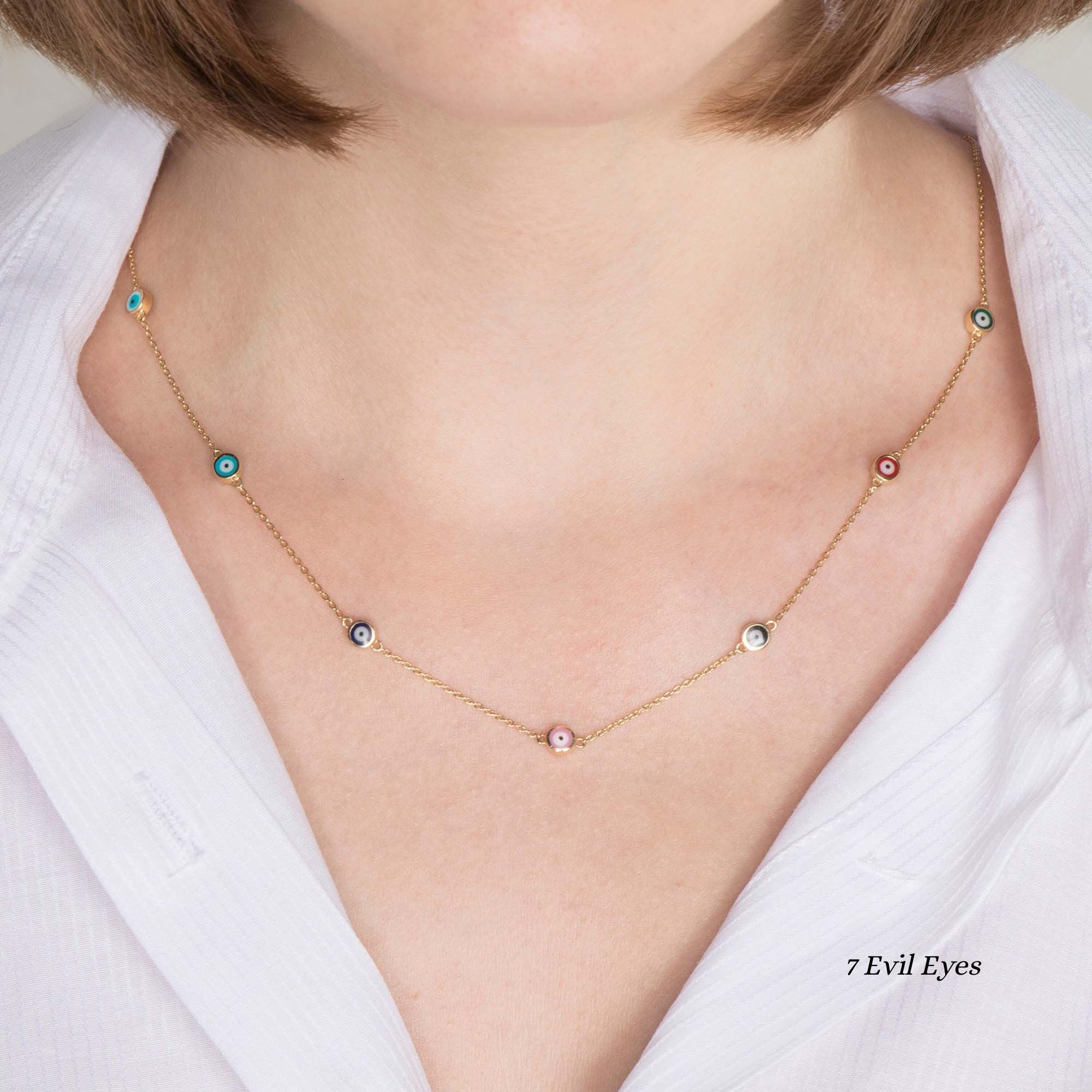Close up of a model wearing  a 7 multicolor evil eye station necklace. 